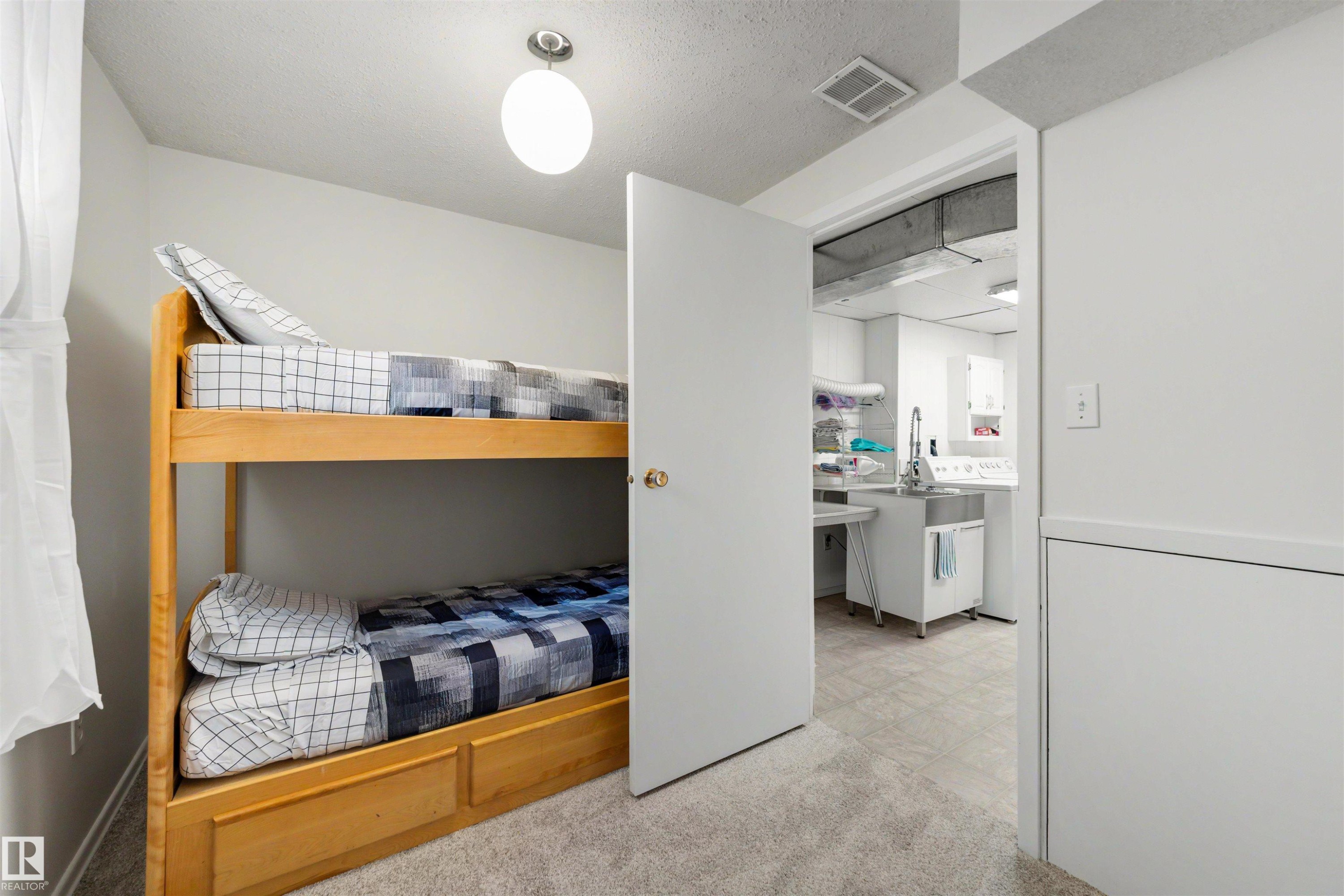 Carpeted room with a built-in wooden bunk bed featuring storage drawers - 9602 85 Street, Edmonton, AB