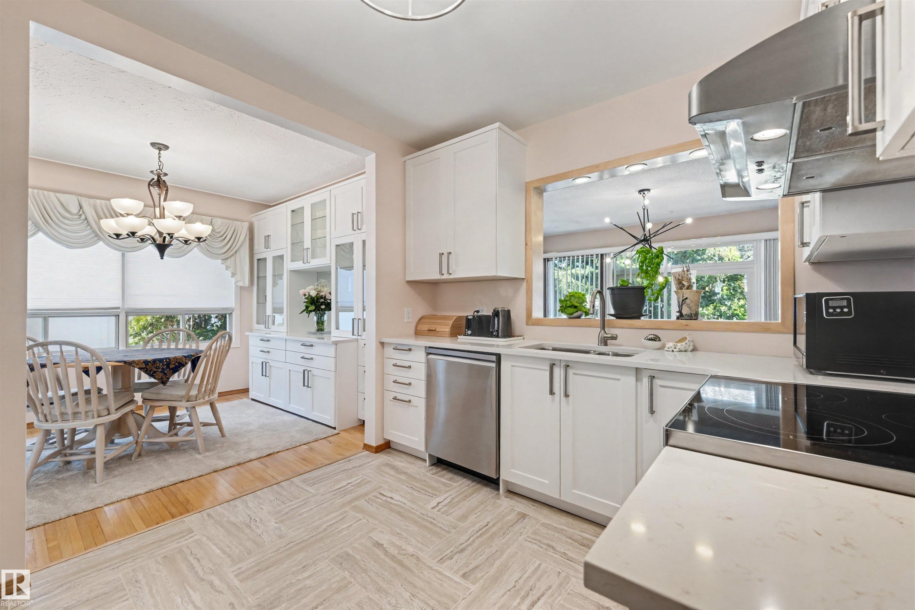 Kitchen featuring white cabinetry, light-toned countertops, and stainless steel appliances including a dishwasher and range hood - 9602 85 Street, Edmonton, AB