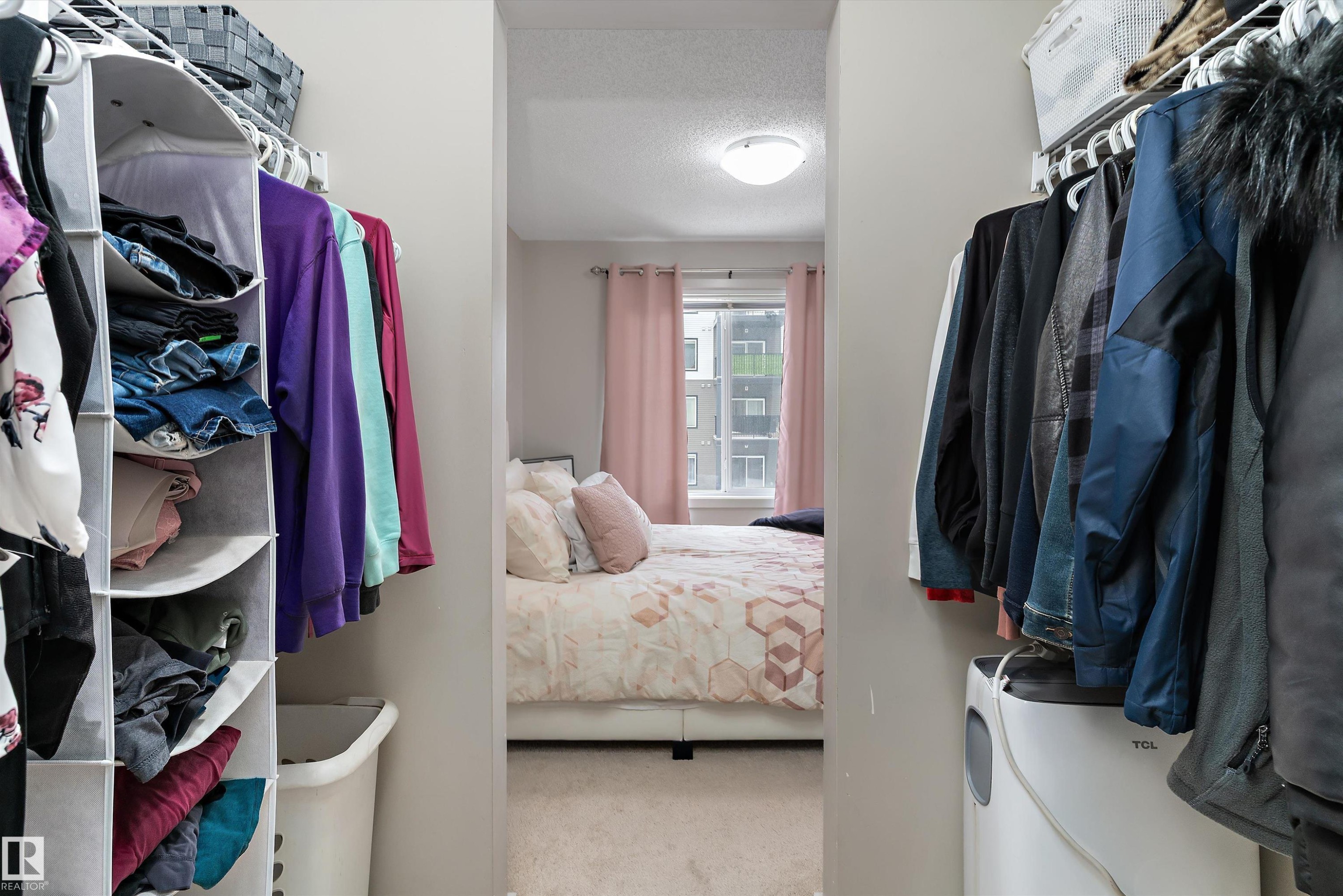 Walk-through closet with built-in wire shelving and a soft carpeted bedroom area - 231 344 Windermere Road, Edmonton, AB - Indoor With Storage