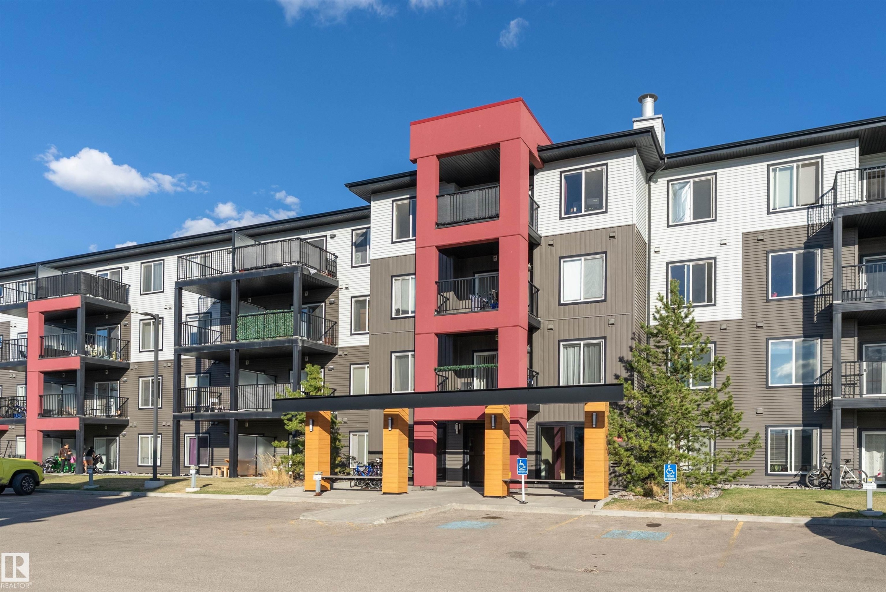 Contemporary multi-story building featuring a red and grey exterior with multiple balconies - 231 344 Windermere Road, Edmonton, AB - Outdoor With Balcony With Facade