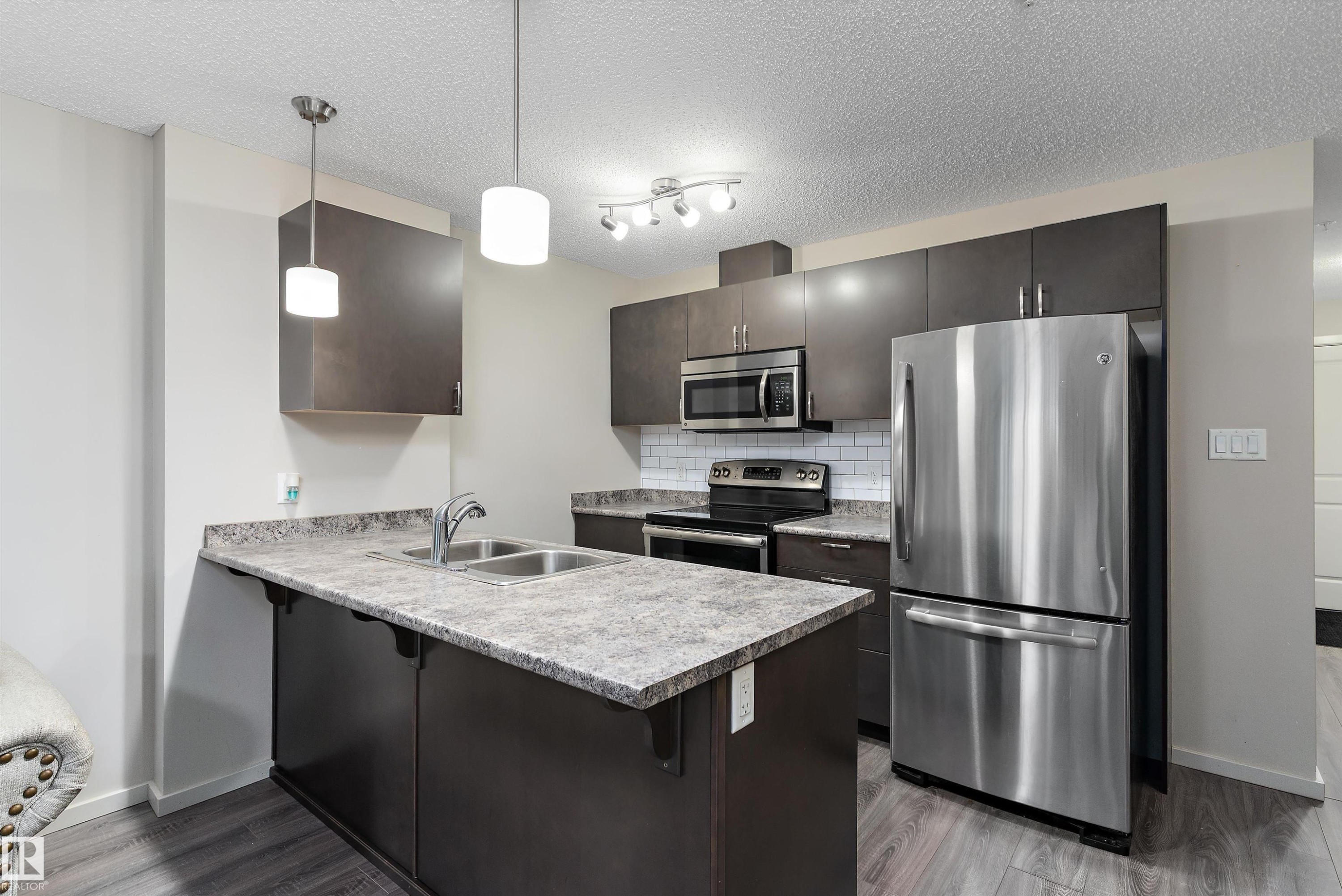 Contemporary kitchen featuring dark wood-finish cabinetry and stainless steel appliances - 231 344 Windermere Road, Edmonton, AB - Indoor Photo Showing Kitchen With Double Sink