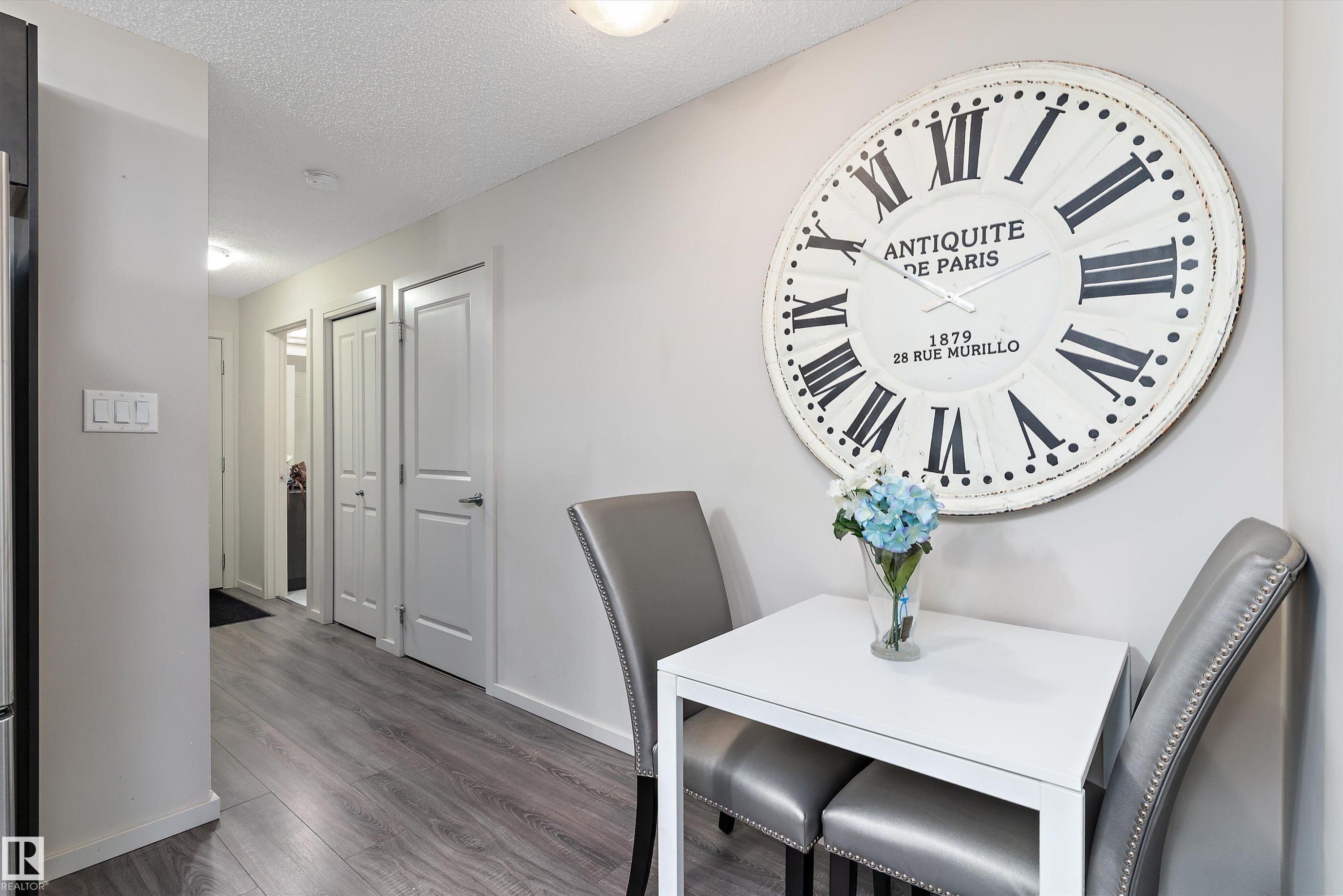 Hallway featuring wood-finish flooring, light grey walls, and ceiling-mounted lighting fixtures - 231 344 Windermere Road, Edmonton, AB - Indoor Photo Showing Dining Room