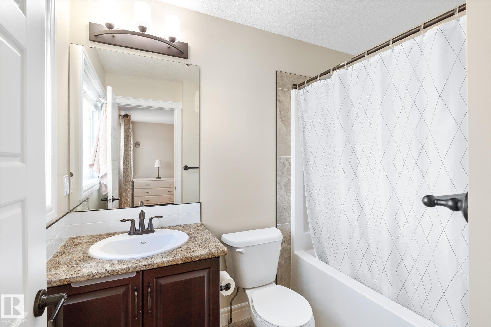 Bathroom featuring a dark wood vanity with a light-colored countertop, an undermount sink, and dark bronze fixtures - 6864 Evans Wynd, Edmonton, AB - Indoor Photo Showing Bathroom