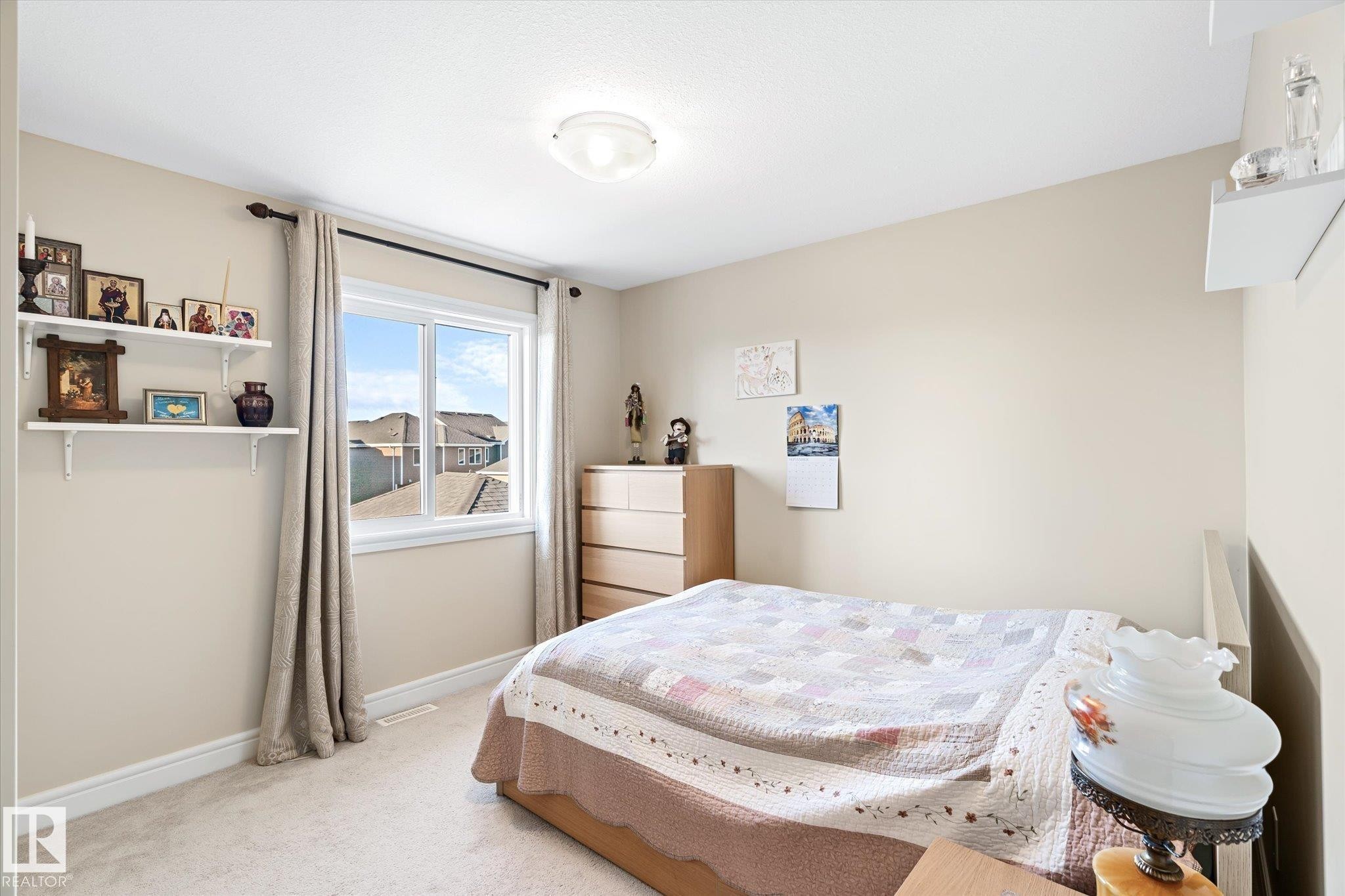 Carpeted room featuring a single window with white trim, neutral wall paint, white baseboards, and a flush-mount ceiling light - 6864 Evans Wynd, Edmonton, AB - Indoor Photo Showing Bedroom