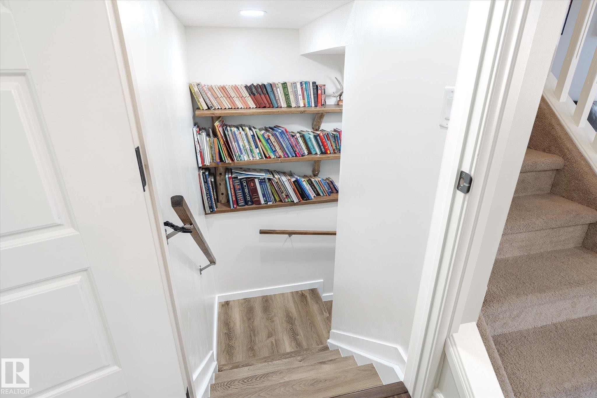Stairwell featuring built-in wooden shelving, recessed lighting, and wood-finish flooring at the base - 6864 Evans Wynd, Edmonton, AB - Indoor Photo Showing Other Room