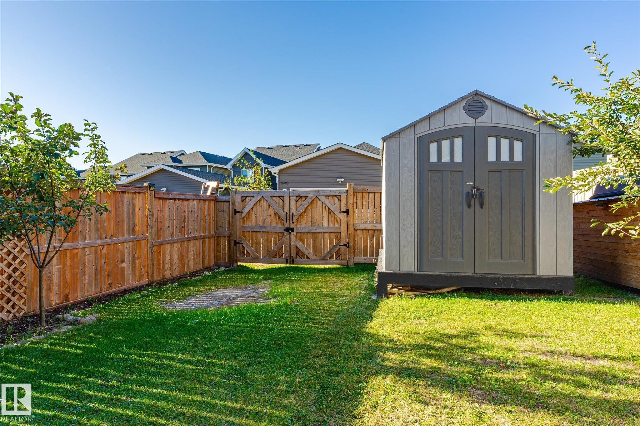Backyard featuring a shed with double doors, wood fencing, and a wood gate - 6864 Evans Wynd, Edmonton, AB - Outdoor