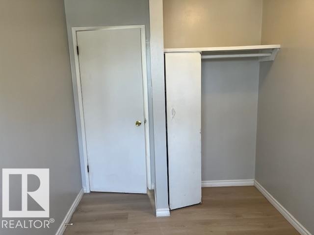 Interior space featuring light wood-finish flooring, light gray wall paint, white baseboards, and a white interior door with brass hardware - 6117 120 Avenue, Edmonton, AB - Indoor Photo Showing Other Room