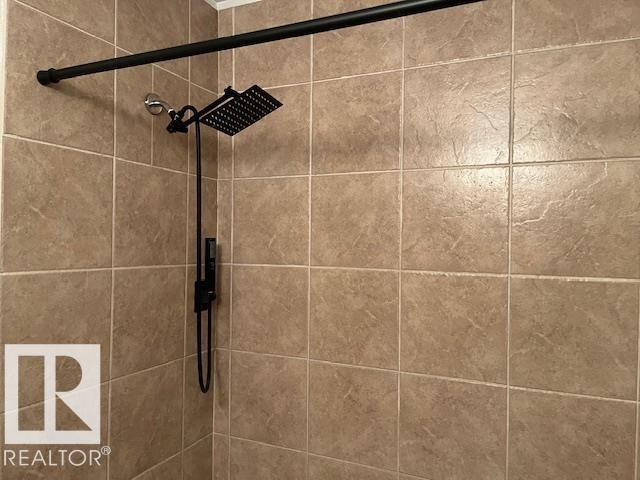 Tiled shower enclosure featuring a matte black rainfall showerhead with an integrated handheld sprayer - 6117 120 Avenue, Edmonton, AB - Indoor Photo Showing Bathroom