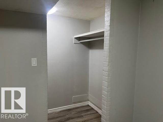 Recessed closet area featuring built-in shelving, a clothes rod, wood-finish flooring, light gray walls, and a recessed ceiling light - 6117 120 Avenue, Edmonton, AB - Indoor