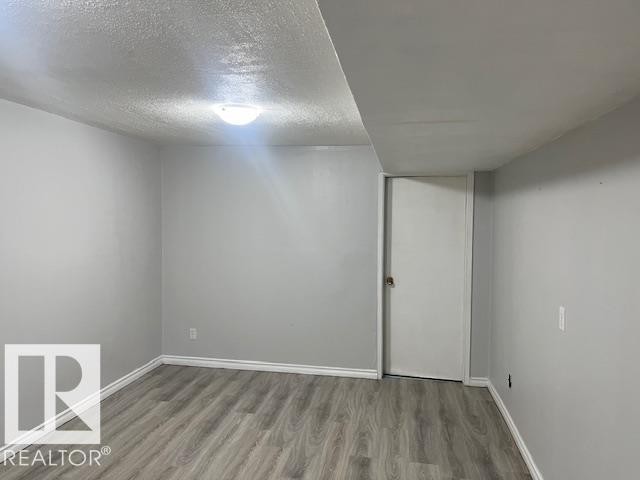 Room featuring light gray walls, wood-finish flooring, white baseboards, and a flush mount ceiling light - 6117 120 Avenue, Edmonton, AB - Indoor Photo Showing Other Room