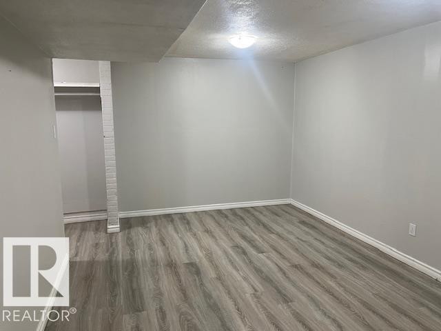 Spacious room featuring wood-finish flooring, light gray walls, white baseboards, and an overhead flush-mount light fixture - 6117 120 Avenue, Edmonton, AB - Indoor Photo Showing Other Room