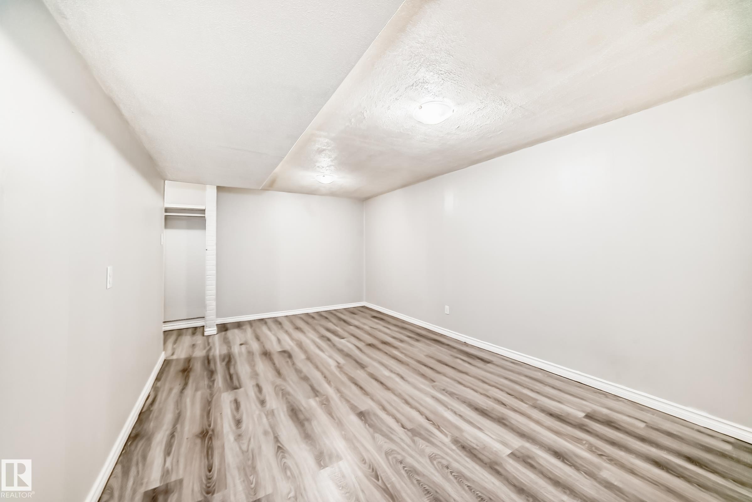 Spacious room featuring wood-finish flooring, light gray walls, white trim, and recessed lighting - 6117 120 Avenue, Edmonton, AB - Indoor Photo Showing Other Room