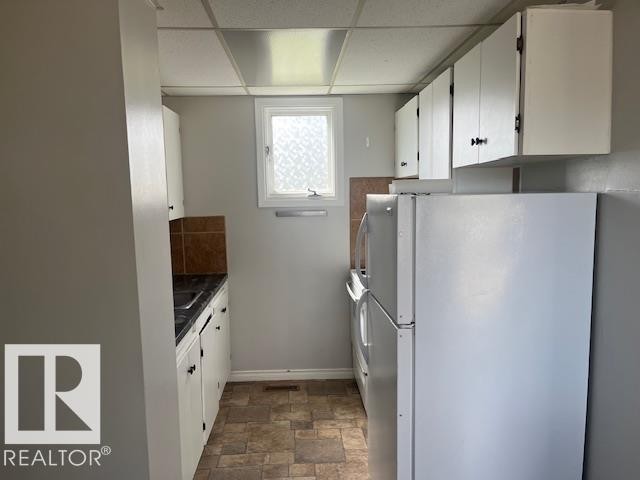 Galley kitchen featuring white cabinetry, dark countertops, and a tile backsplash - 6117 120 Avenue, Edmonton, AB - Indoor