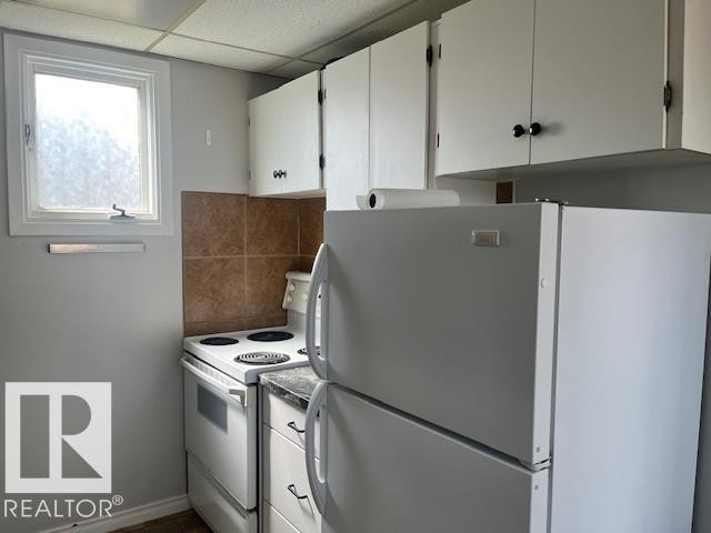 Kitchen featuring white cabinetry with dark hardware, a white refrigerator, a white electric range, and a tiled backsplash - 6117 120 Avenue, Edmonton, AB - Indoor Photo Showing Kitchen