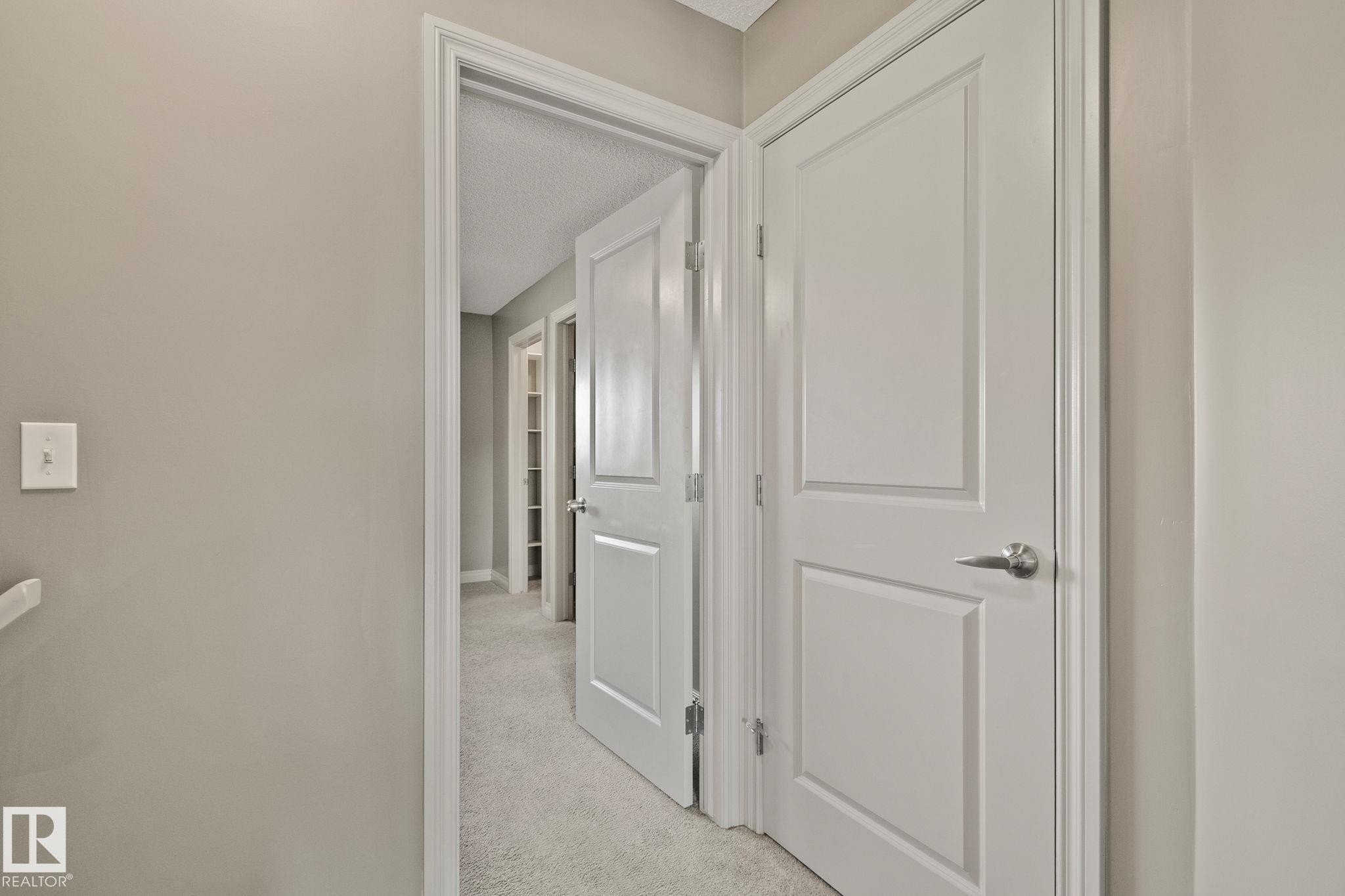 Interior hallway featuring neutral-toned walls, white trim, and light gray carpet - 46 445 Brintnell Boulevard, Edmonton, AB - Indoor Photo Showing Other Room