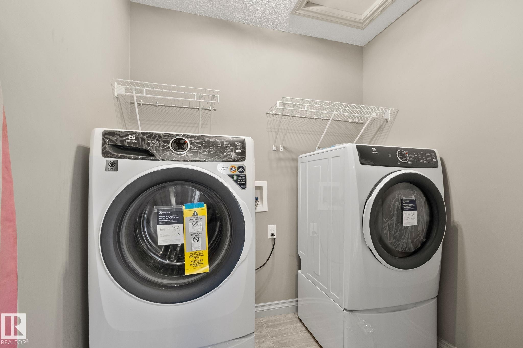 Laundry area featuring a side-by-side washer and dryer, wire shelving, and a textured ceiling - 46 445 Brintnell Boulevard, Edmonton, AB - Indoor Photo Showing Laundry Room
