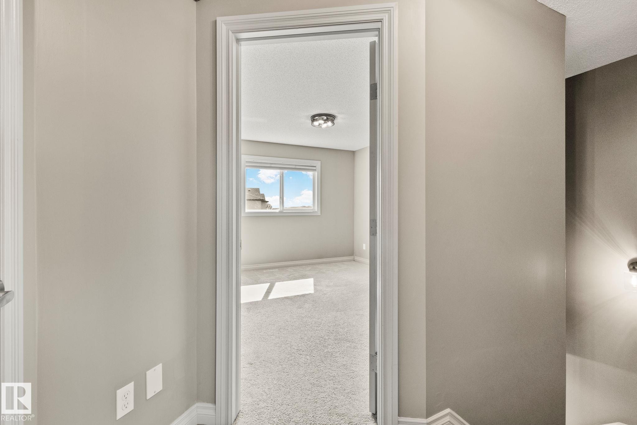 Carpeted interior room with neutral-toned walls, a window, and a flush-mount ceiling light fixture - 46 445 Brintnell Boulevard, Edmonton, AB - Indoor Photo Showing Other Room