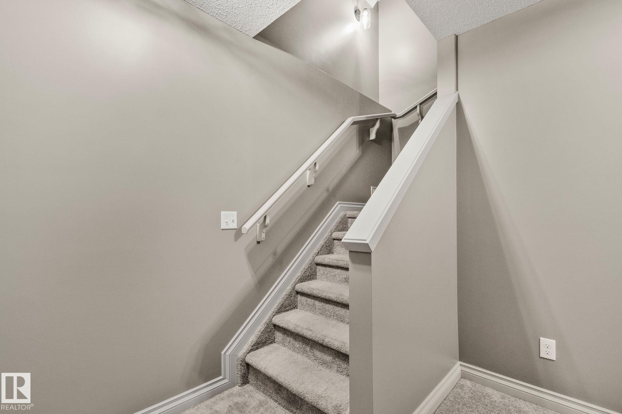 Staircase featuring carpeted treads, white painted risers, and a coordinating white handrail - 46 445 Brintnell Boulevard, Edmonton, AB - Indoor Photo Showing Other Room