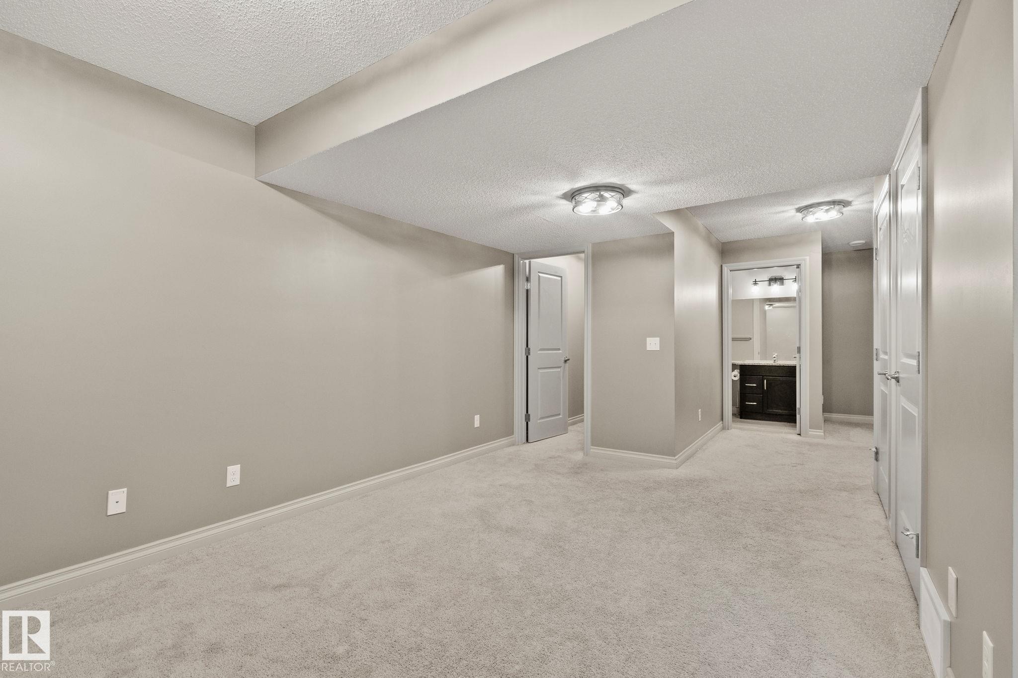 Carpeted room with neutral paint, two flush-mount ceiling lights, and multiple white panel doors - 46 445 Brintnell Boulevard, Edmonton, AB - Indoor Photo Showing Other Room
