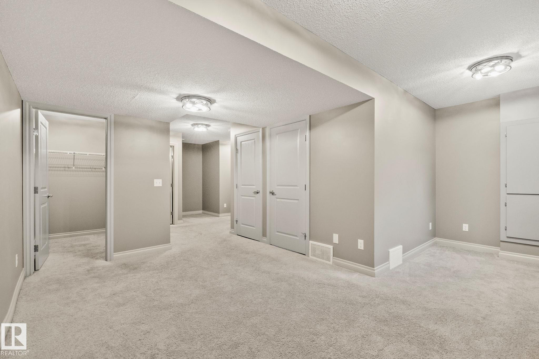 Spacious room featuring light gray carpeting, neutral wall paint, and multiple white panel doors - 46 445 Brintnell Boulevard, Edmonton, AB - Indoor Photo Showing Other Room