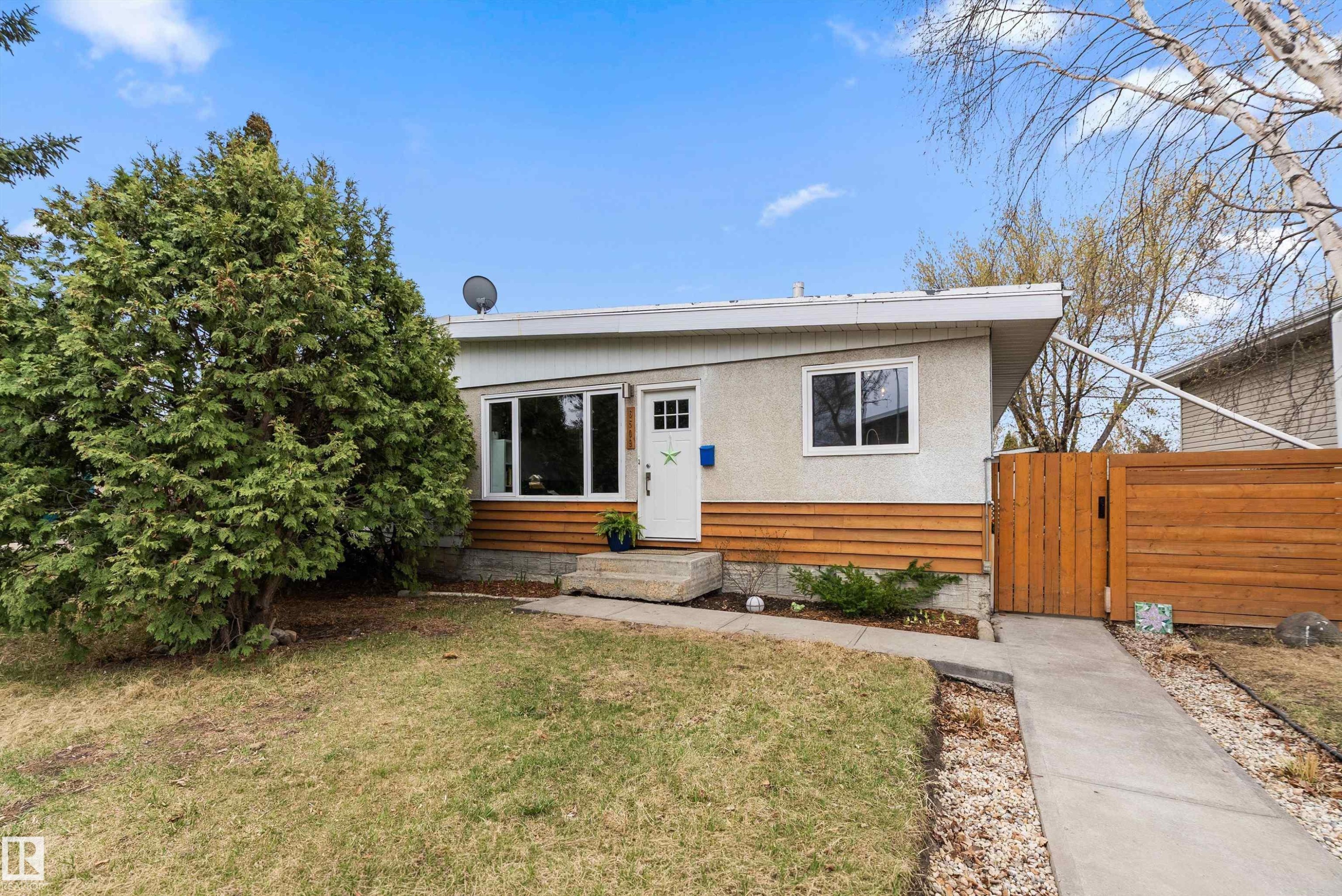 Exterior featuring a white entry door, horizontal wood paneling, and stucco siding - 6509 90 Avenue, Edmonton, AB