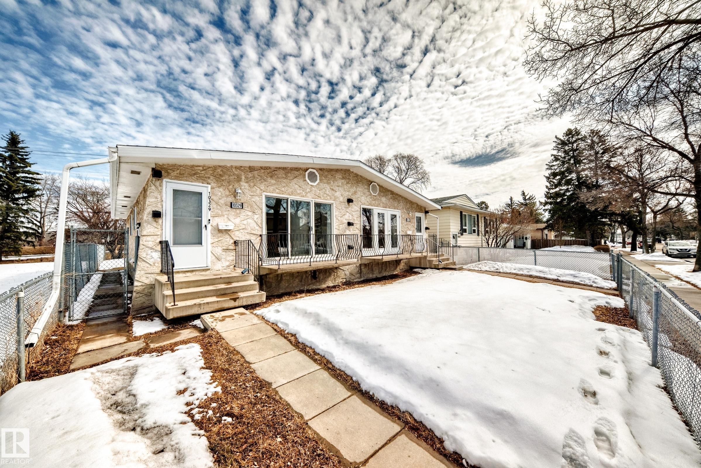 The property features an exterior with stone cladding, a front entrance with steps and a handrail, and a sidewalk leading to the front door - 10329 150 Street, Edmonton, AB - Outdoor
