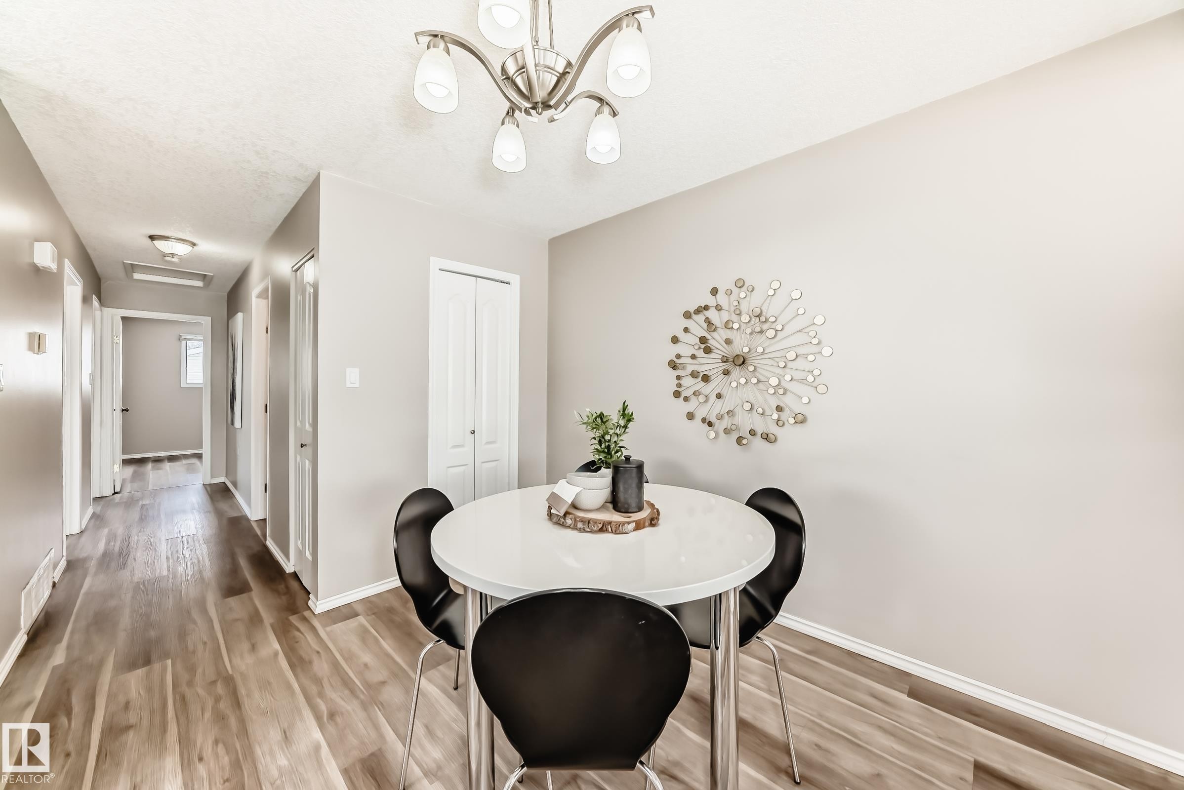 Dining area featuring a modern chandelier, light-colored walls, and wood-look flooring - 10329 150 Street, Edmonton, AB - Indoor Photo Showing Dining Room