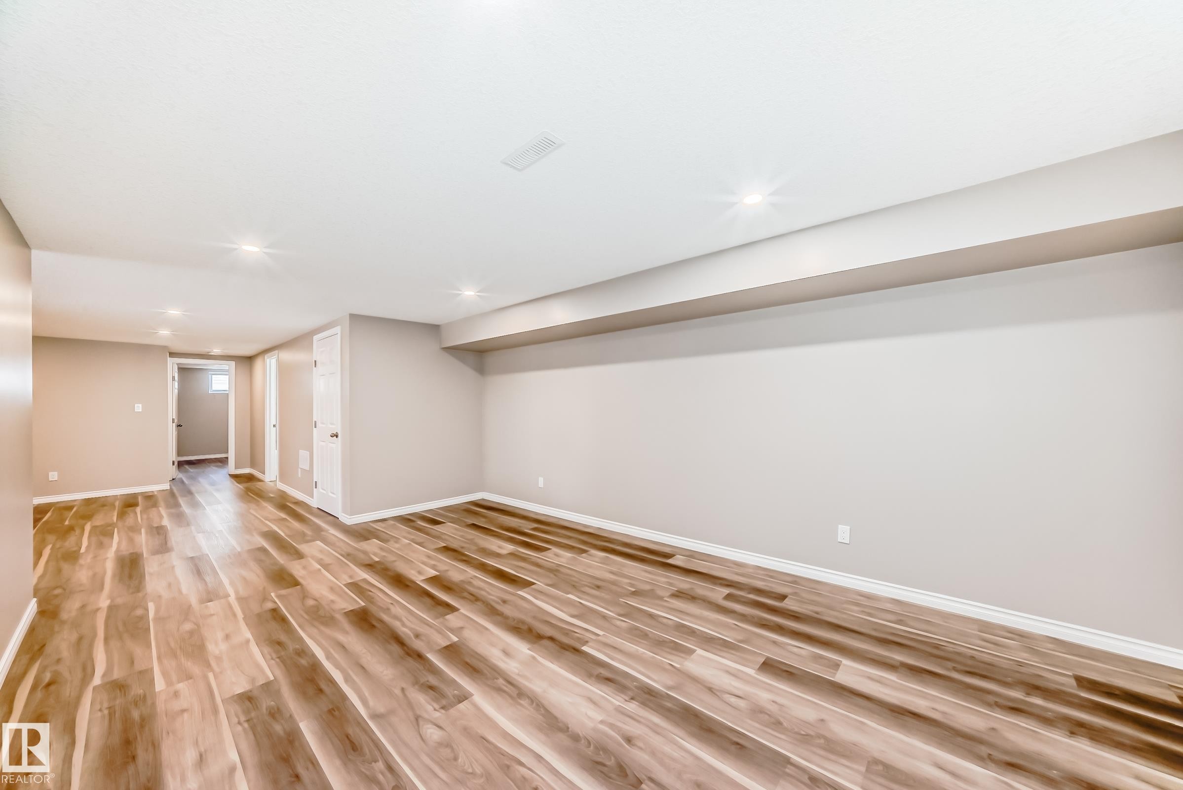 The property features a spacious room with wood-look flooring and recessed lighting - 10329 150 Street, Edmonton, AB - Indoor Photo Showing Other Room