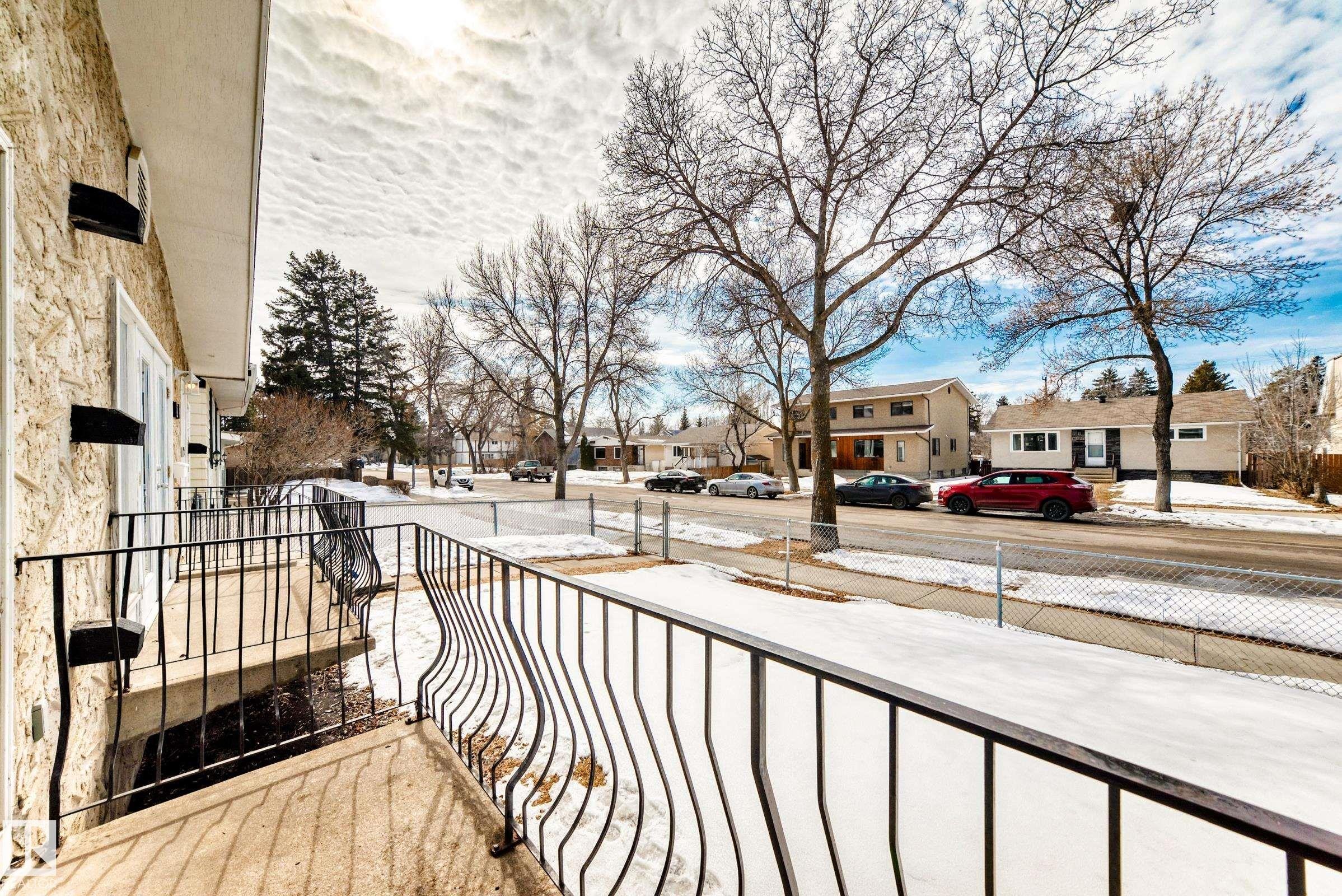 The property features a balcony with black metal railings, offering a view of the street with other properties and bare trees - 10329 150 Street, Edmonton, AB - Outdoor With Balcony