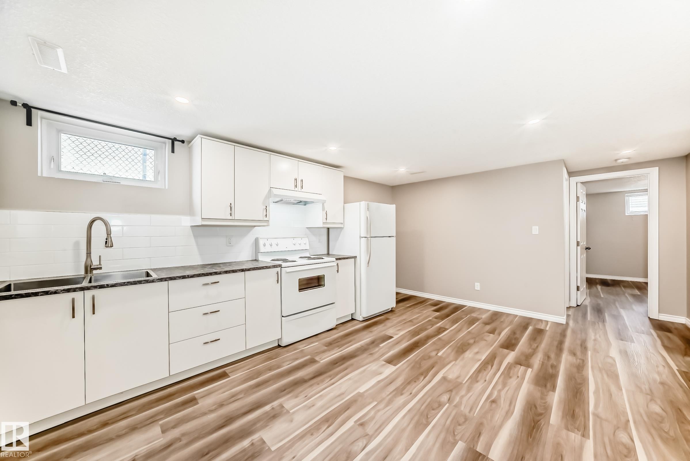 The kitchen features white cabinetry, a white subway tile backsplash, and a double basin stainless steel sink with a gooseneck faucet - 10329 150 Street, Edmonton, AB - Indoor Photo Showing Kitchen