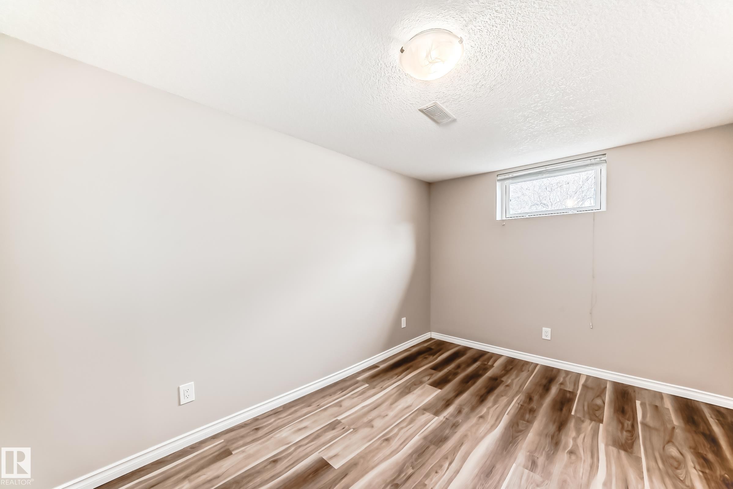 This room features wood-style flooring, light-toned walls, and a ceiling-mounted light fixture - 10329 150 Street, Edmonton, AB - Indoor Photo Showing Other Room