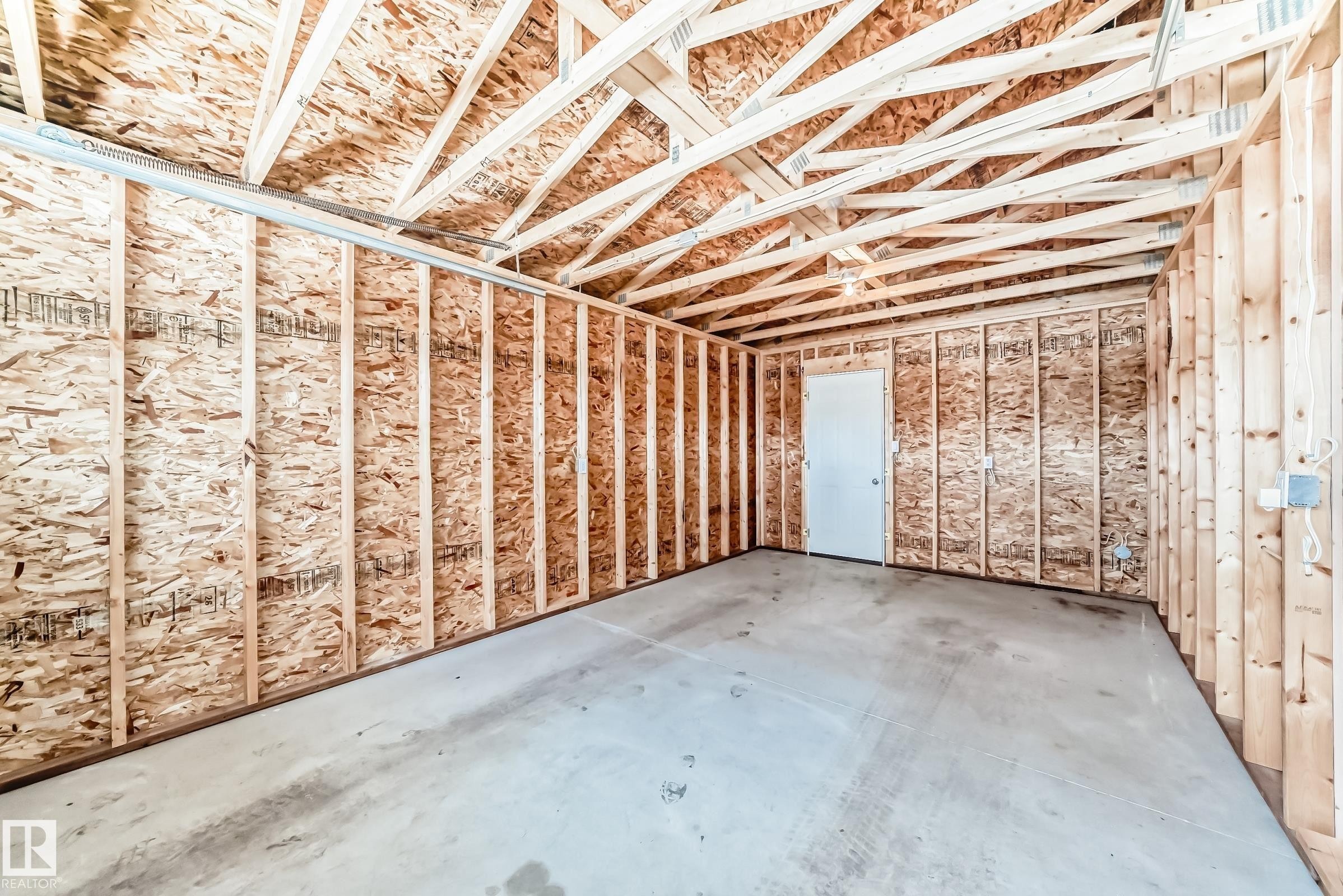 This spacious room features exposed wooden trusses and framing, oriented strand board walls, and a concrete floor - 10329 150 Street, Edmonton, AB - Indoor