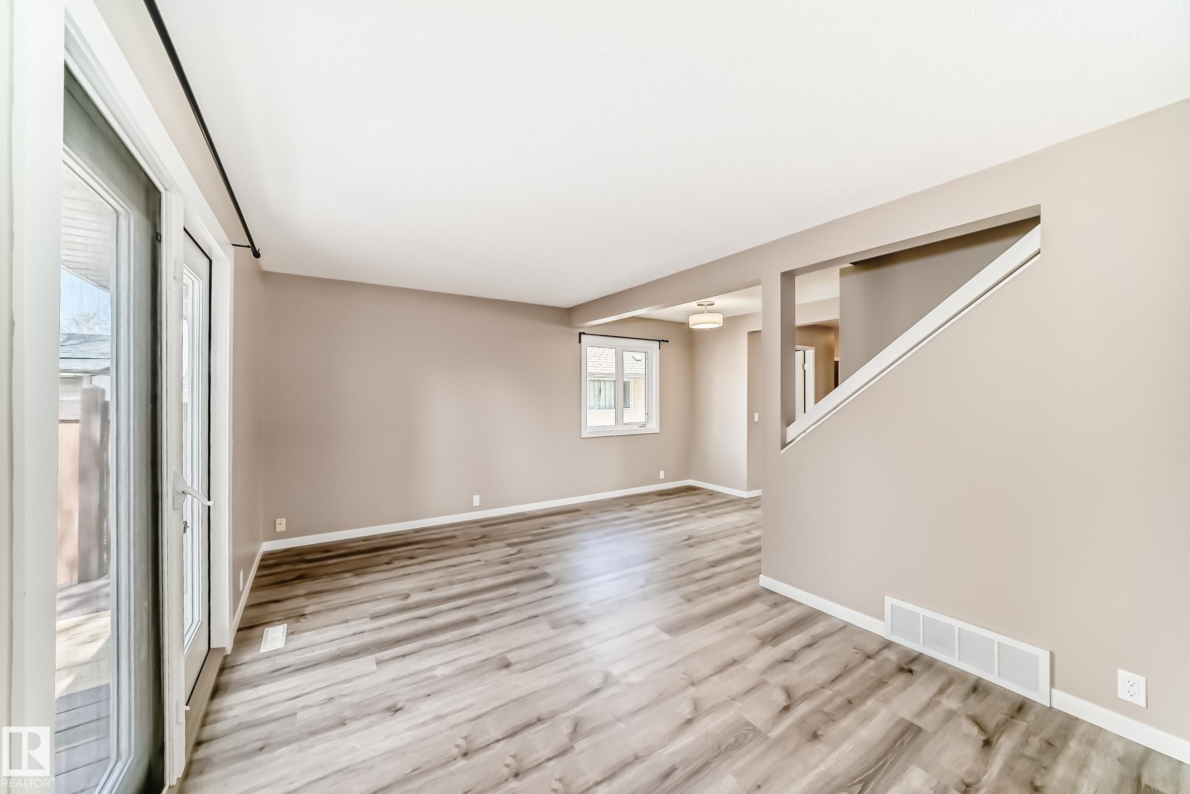 Spacious living area featuring wood-finish flooring, neutral wall tones, and white trim - 2578 138A Avenue, Edmonton, AB - Indoor Photo Showing Other Room