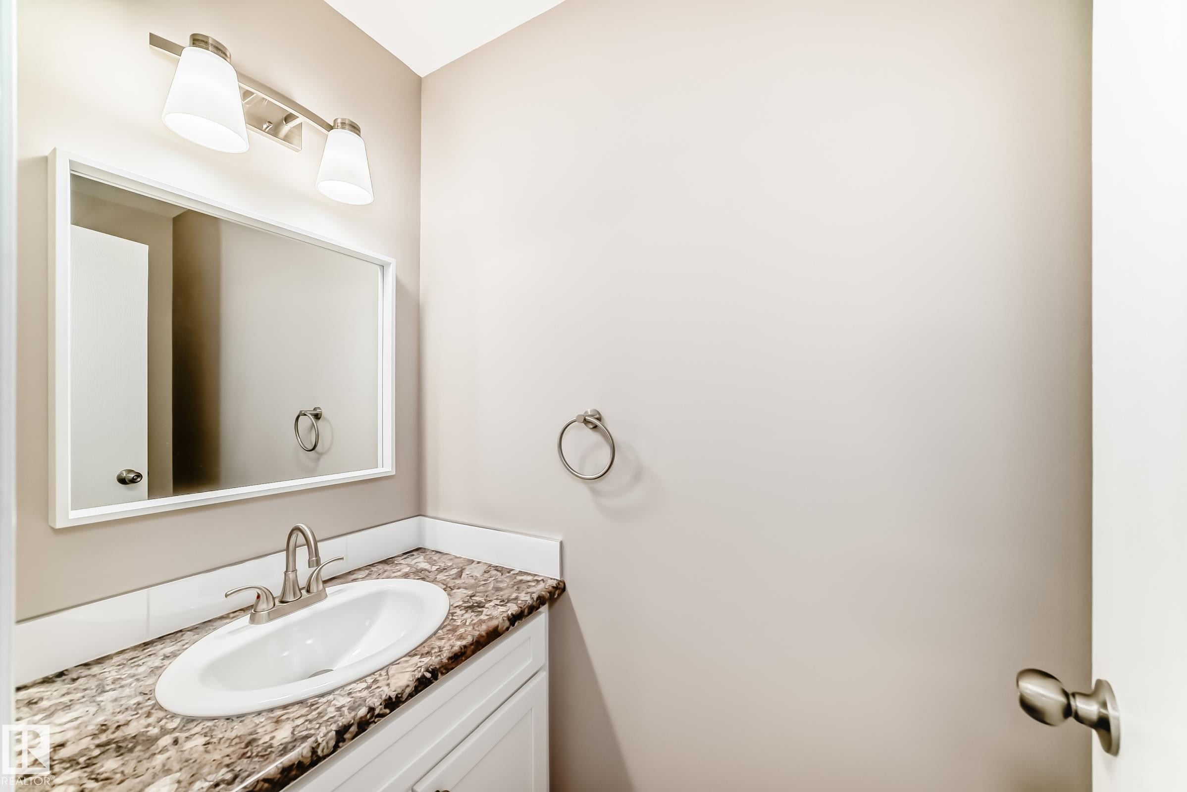 Bathroom vanity featuring an integrated oval sink, a patterned countertop, and a white base cabinet - 2578 138A Avenue, Edmonton, AB - Indoor Photo Showing Bathroom
