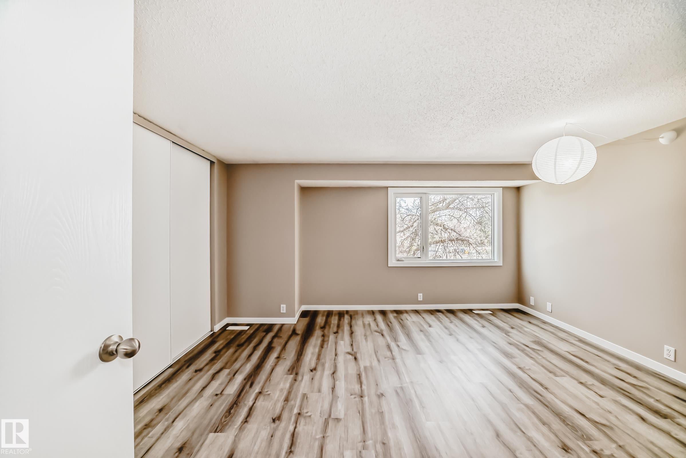 Spacious room featuring wood-finish flooring, neutral-toned walls, and a large window - 2578 138A Avenue, Edmonton, AB - Indoor Photo Showing Other Room