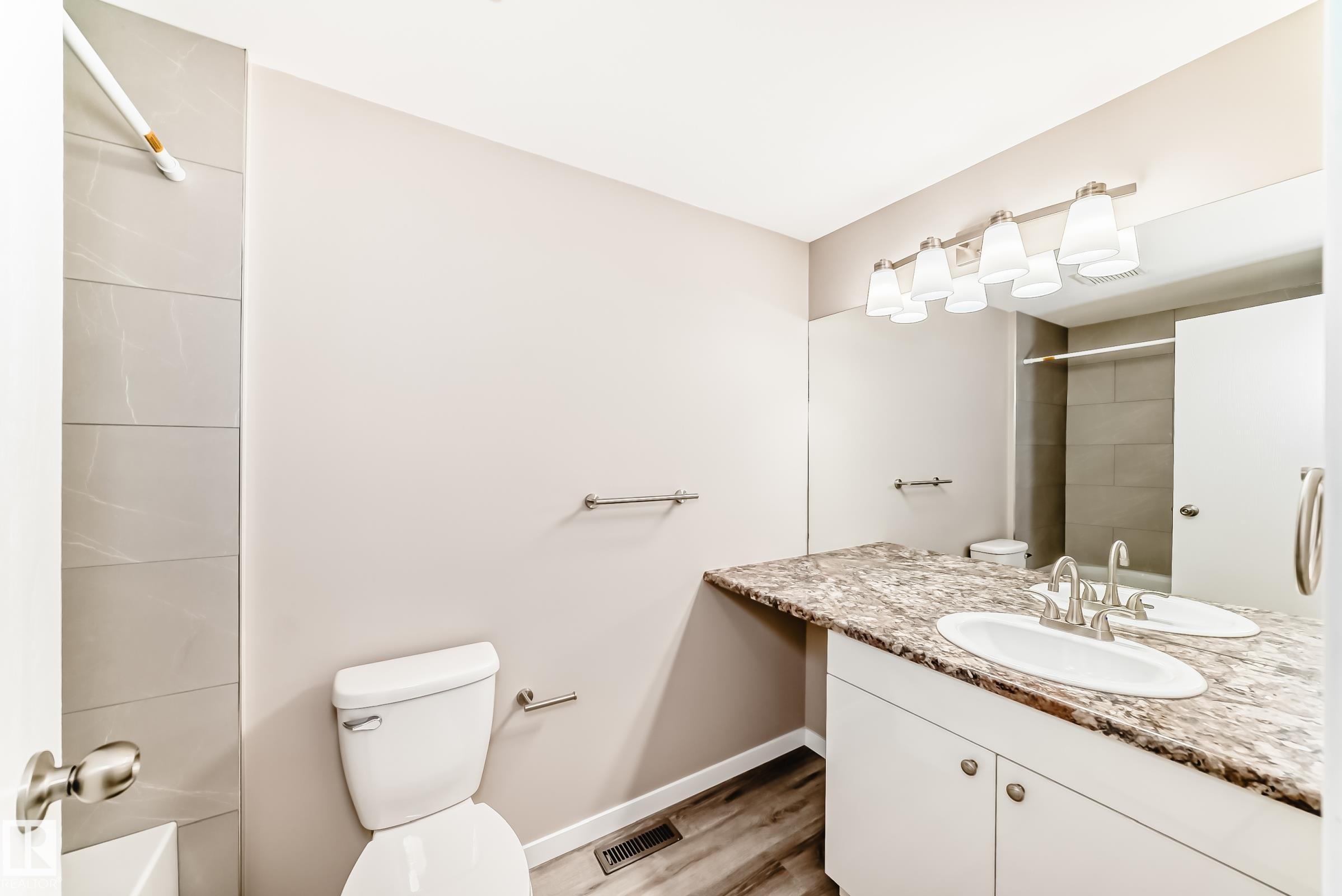 Bathroom featuring a vanity with a stone-look countertop, undermount sink, and brushed nickel fixtures - 2578 138A Avenue, Edmonton, AB - Indoor Photo Showing Bathroom