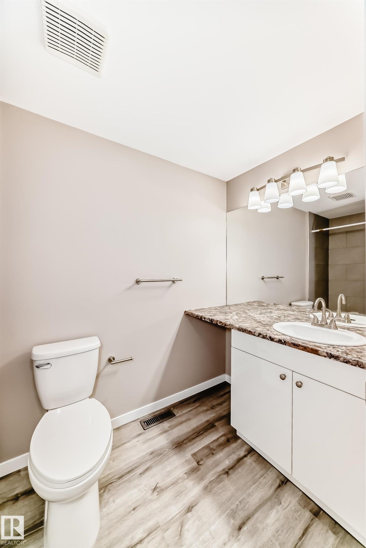 Bathroom featuring a white vanity with a single basin, a mottled countertop, and wood-finish flooring - 2578 138A Avenue, Edmonton, AB - Indoor Photo Showing Bathroom