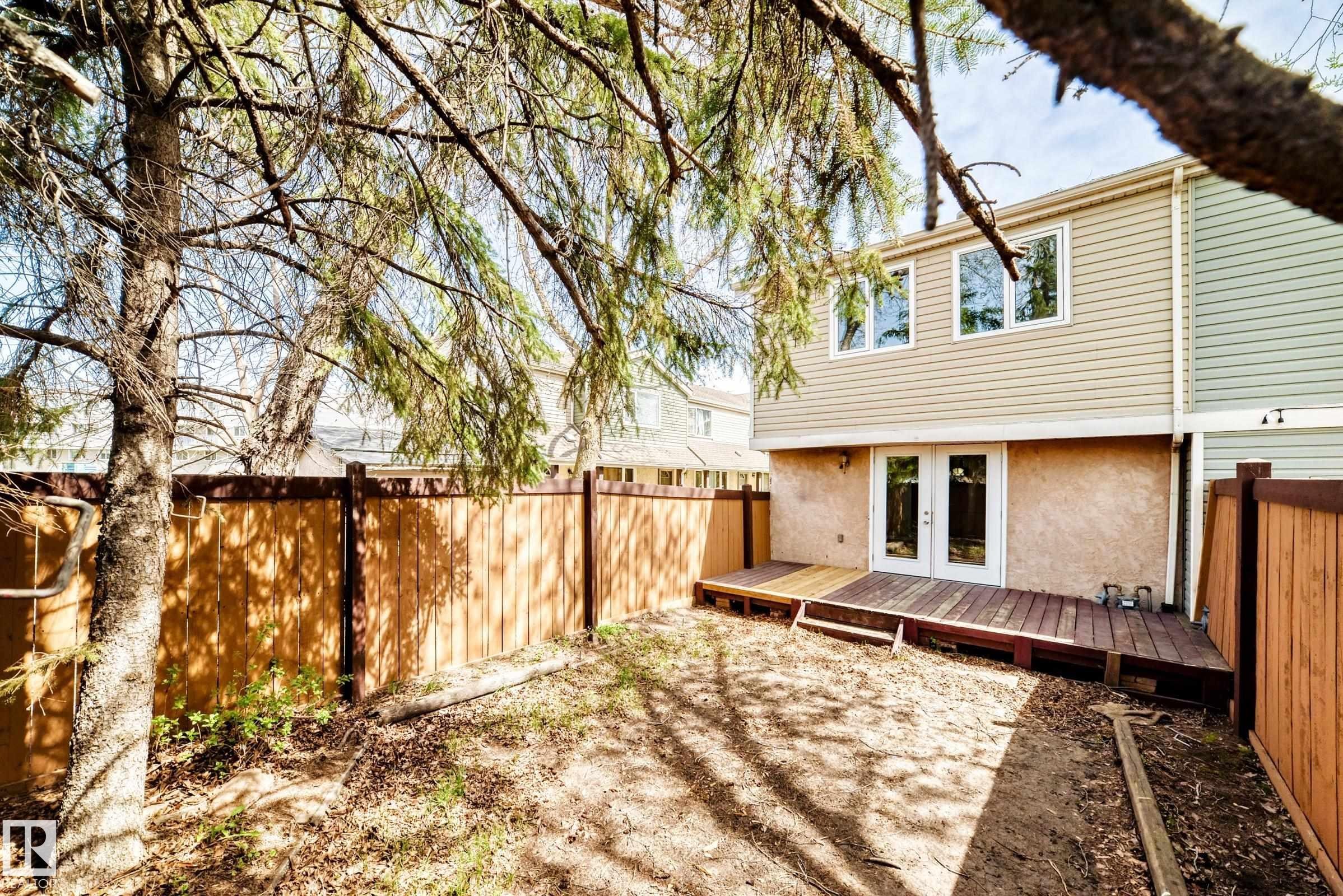 Rear exterior featuring a multi-level wood deck, white French doors, and two upper-level windows - 2578 138A Avenue, Edmonton, AB - Outdoor