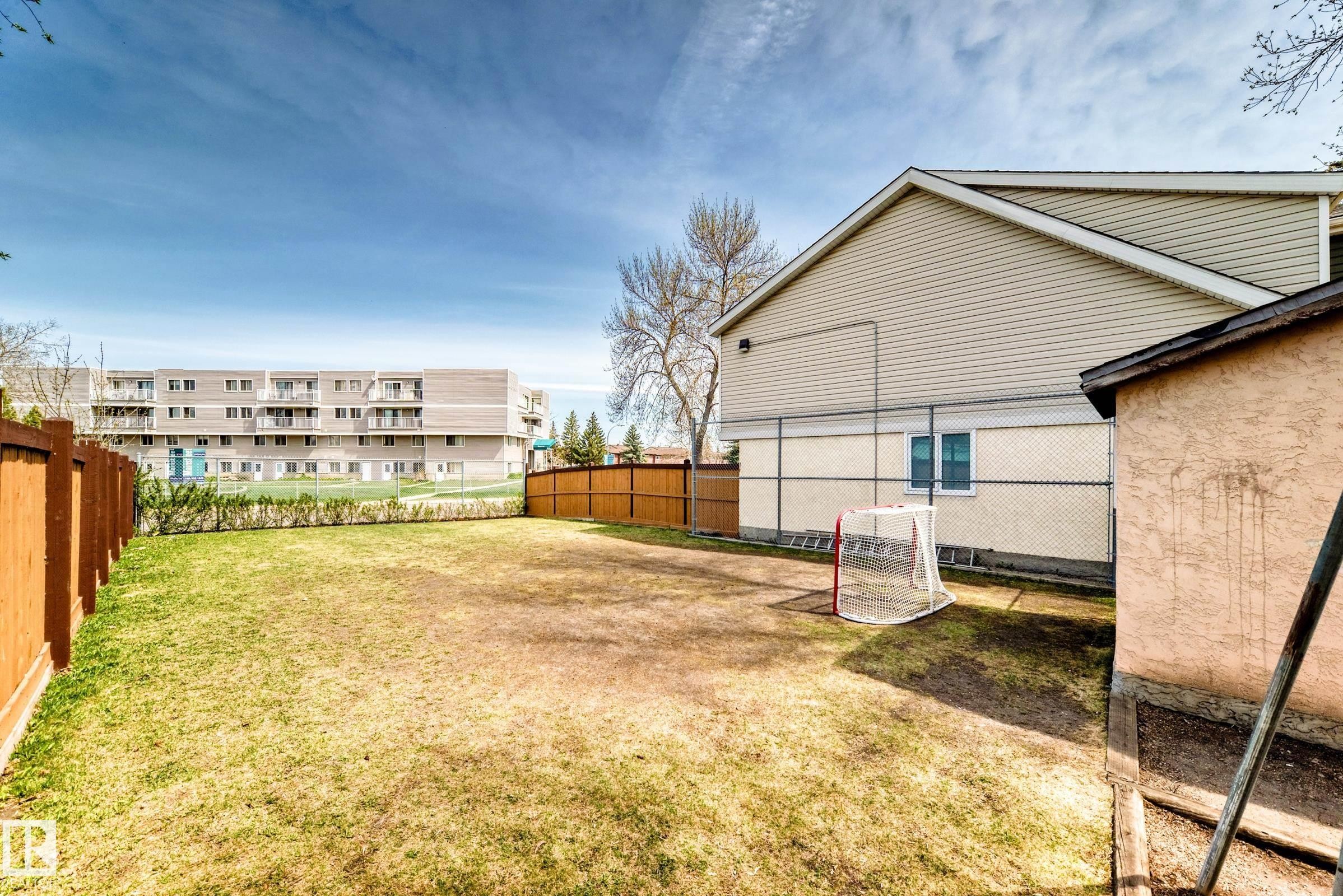 Expansive backyard with a mix of grass and natural ground cover, featuring a new wood fence on two sides - 2578 138A Avenue, Edmonton, AB - Outdoor
