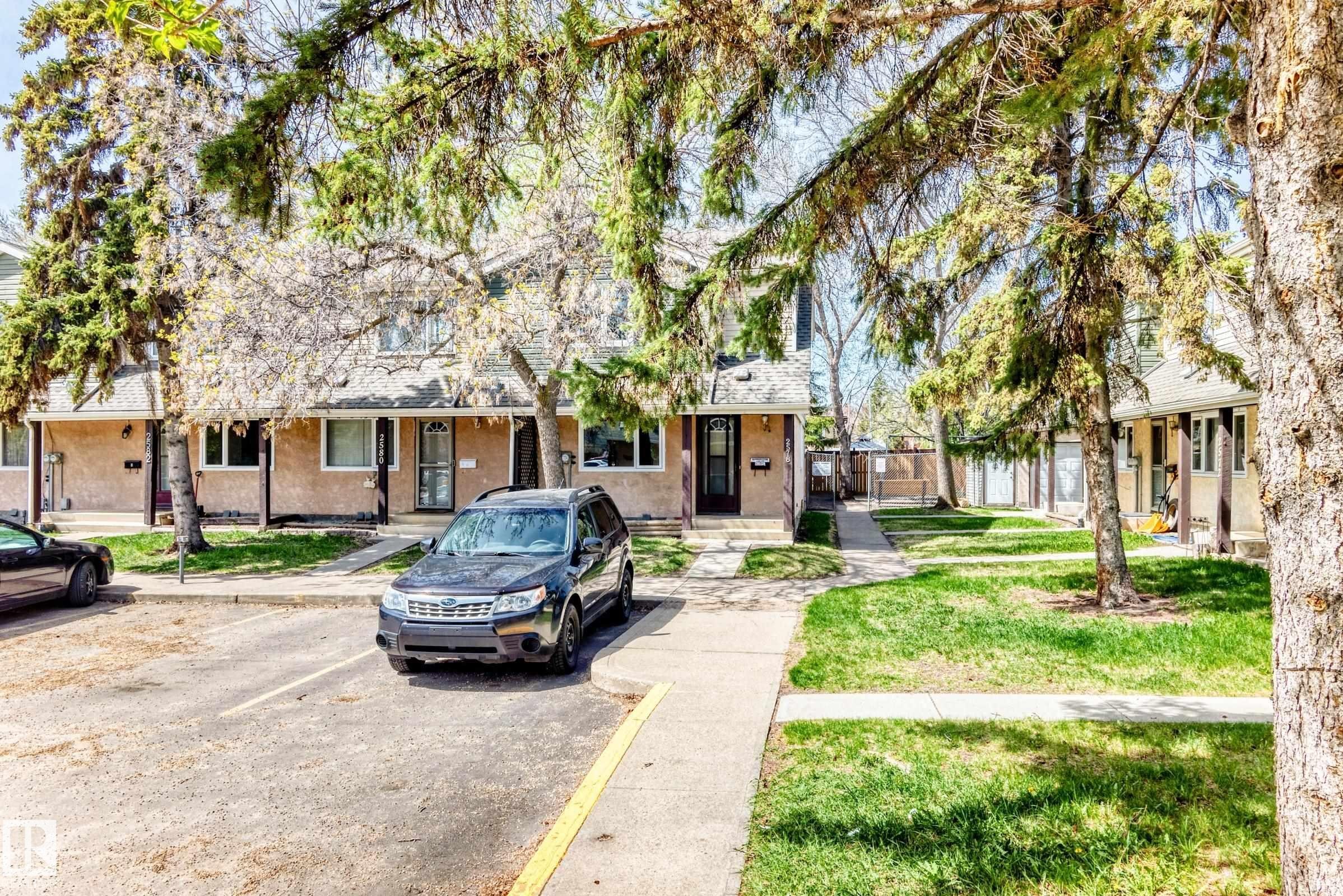 Townhouse facade featuring beige stucco exterior, white trim windows, and dark entry doors - 2578 138A Avenue, Edmonton, AB - Outdoor