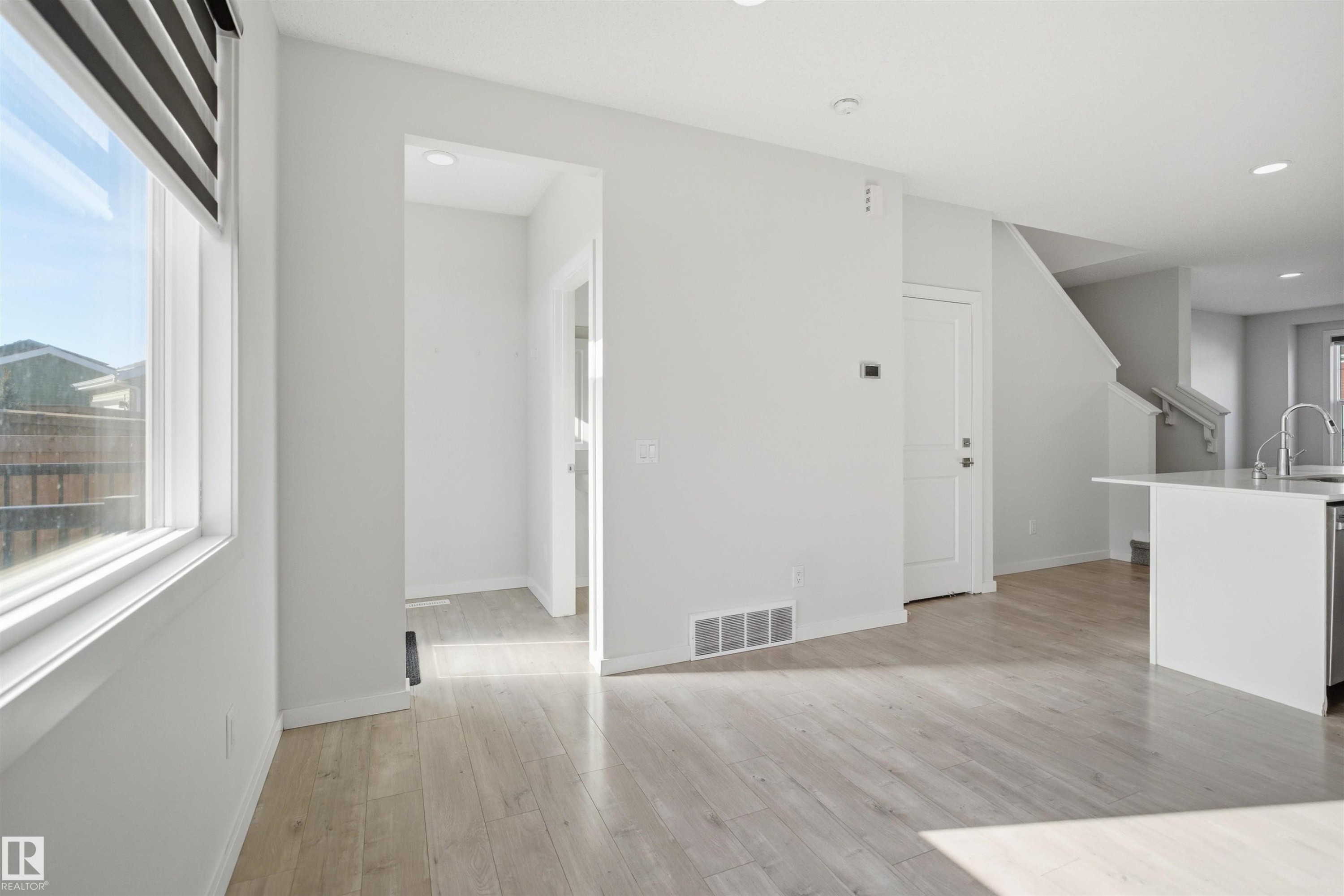 This bright interior features light-toned flooring, a window with horizontal blinds, and a white interior door - 2125 Maple Road Nw, Edmonton, AB - Indoor