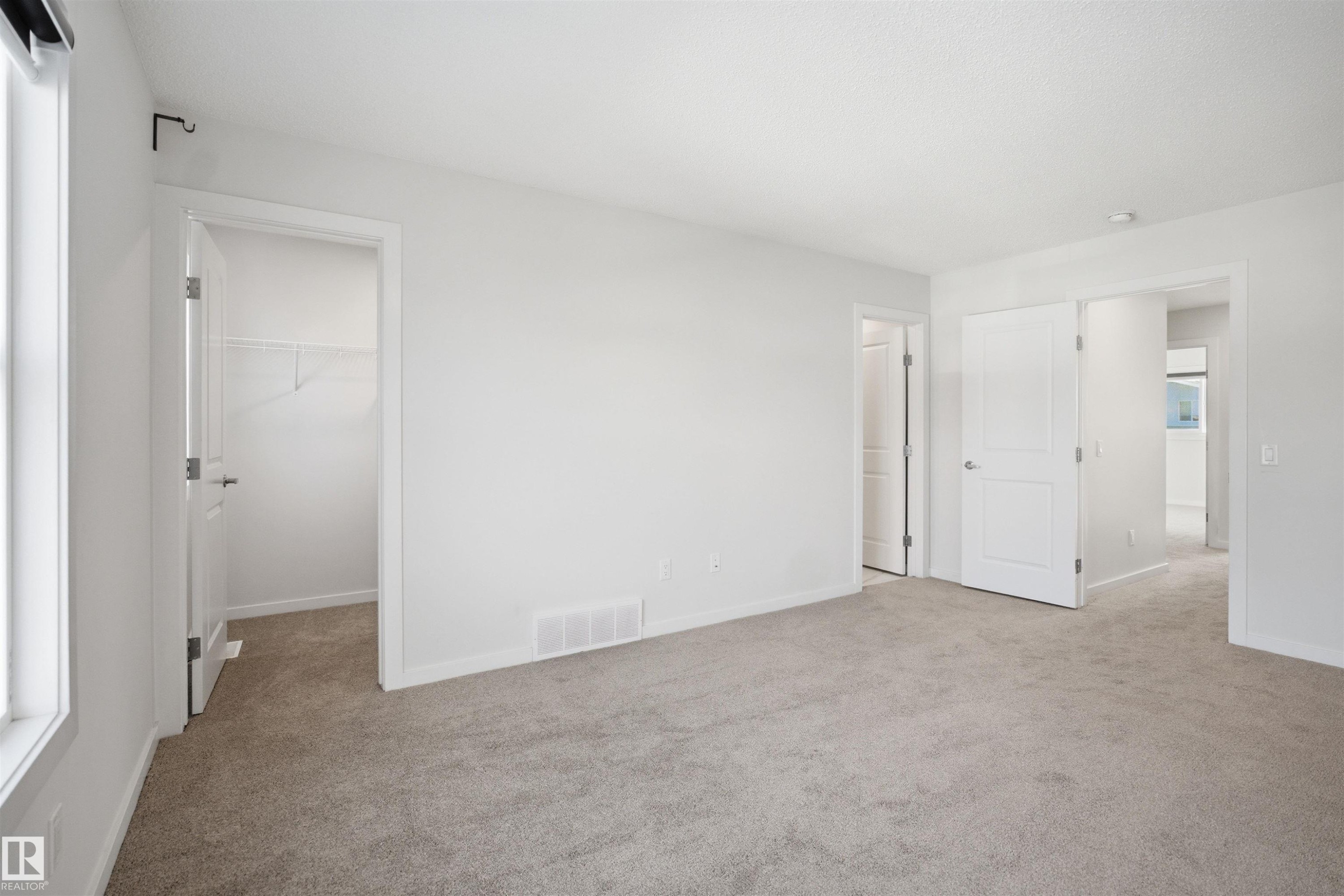 Spacious room featuring light-colored carpet flooring, white walls, and a window with a white frame - 2125 Maple Road Nw, Edmonton, AB - Indoor Photo Showing Other Room