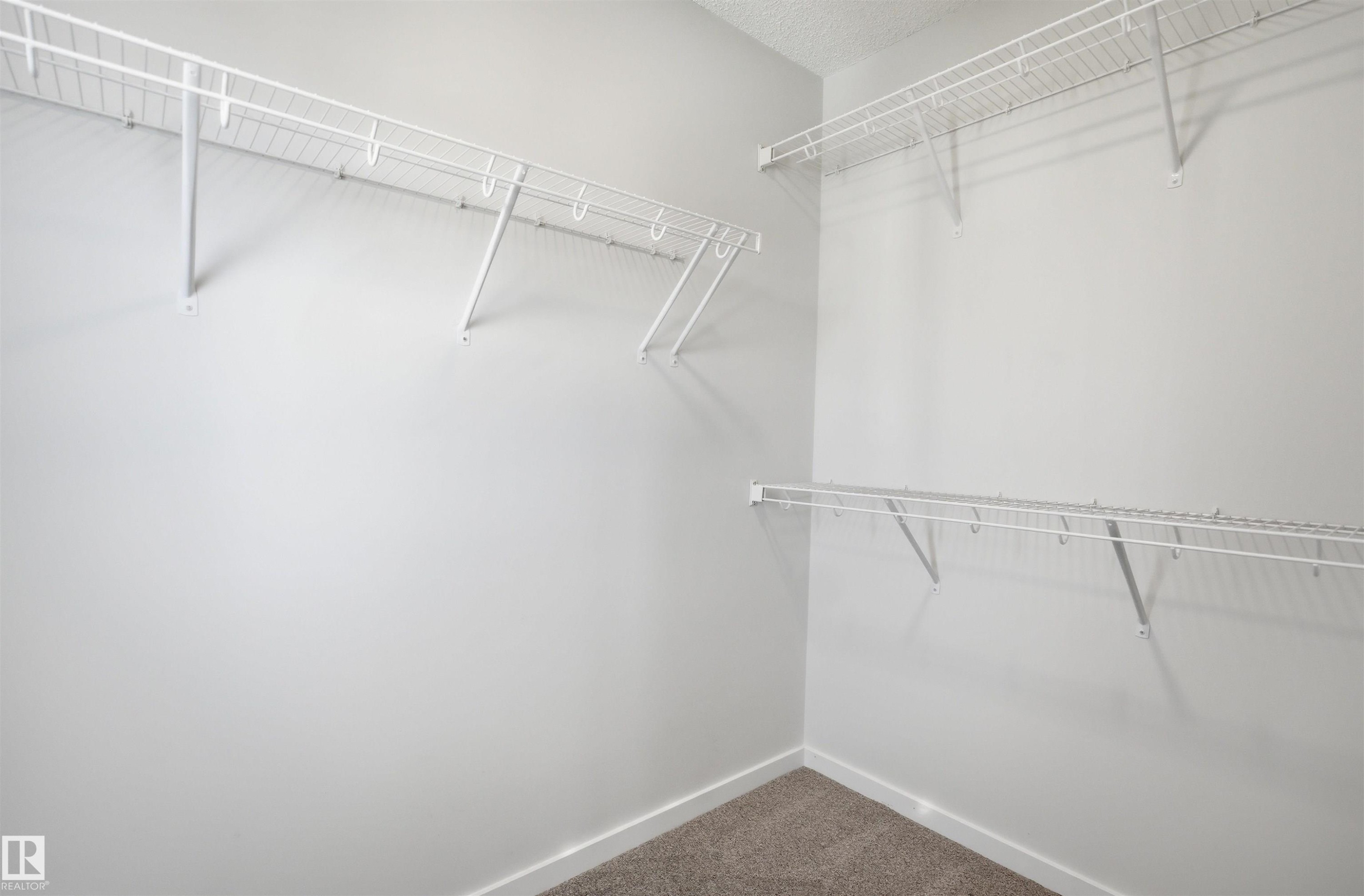 The property includes a walk-in closet with white wire shelving units and carpeting - 2125 Maple Road Nw, Edmonton, AB - Indoor With Storage