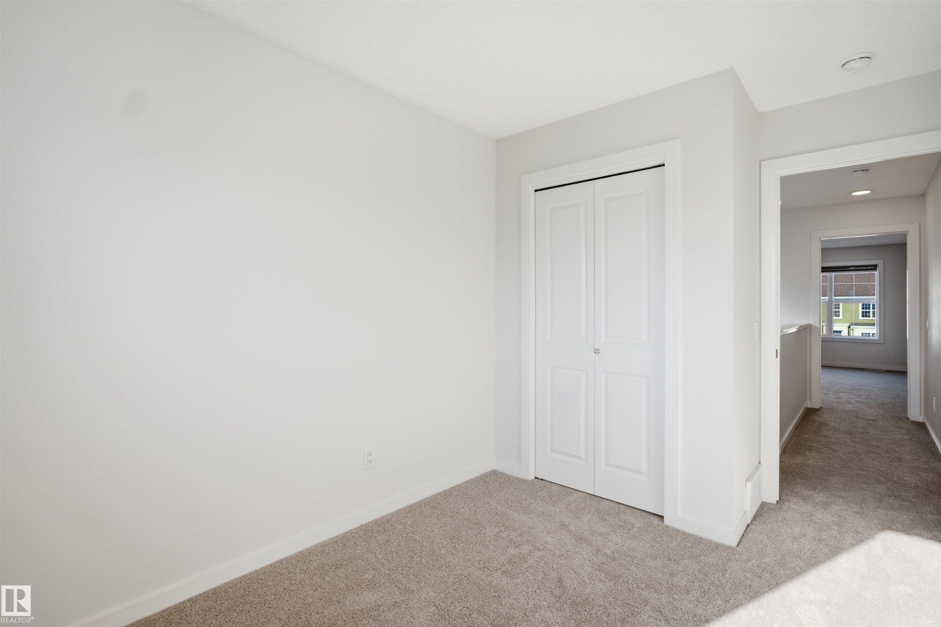 This room features neutral-toned carpet flooring and light-colored walls, providing a versatile backdrop - 2125 Maple Road Nw, Edmonton, AB - Indoor Photo Showing Other Room
