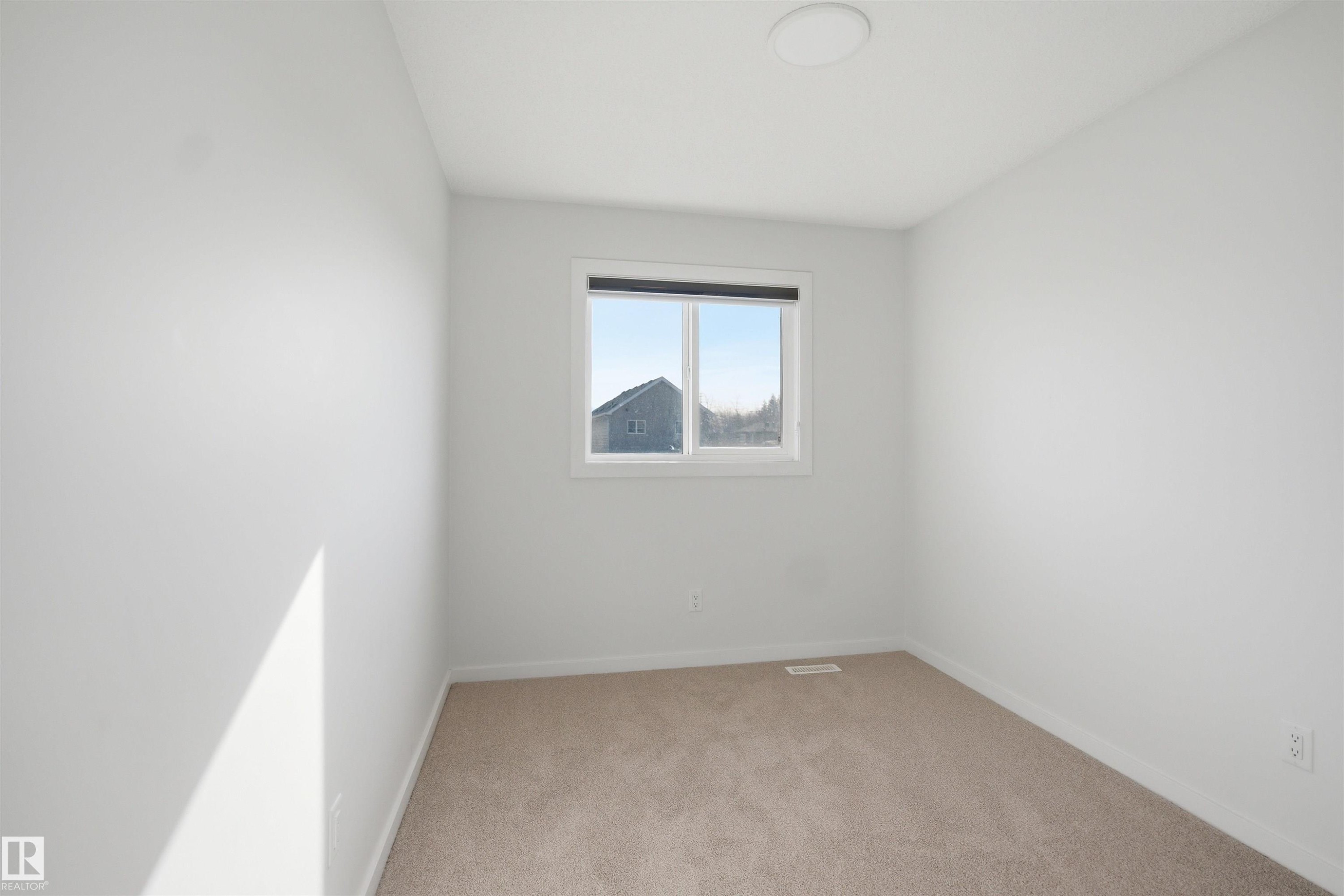 Bright room featuring light-colored carpet, white walls, and a window providing natural light - 2125 Maple Road Nw, Edmonton, AB - Indoor Photo Showing Other Room