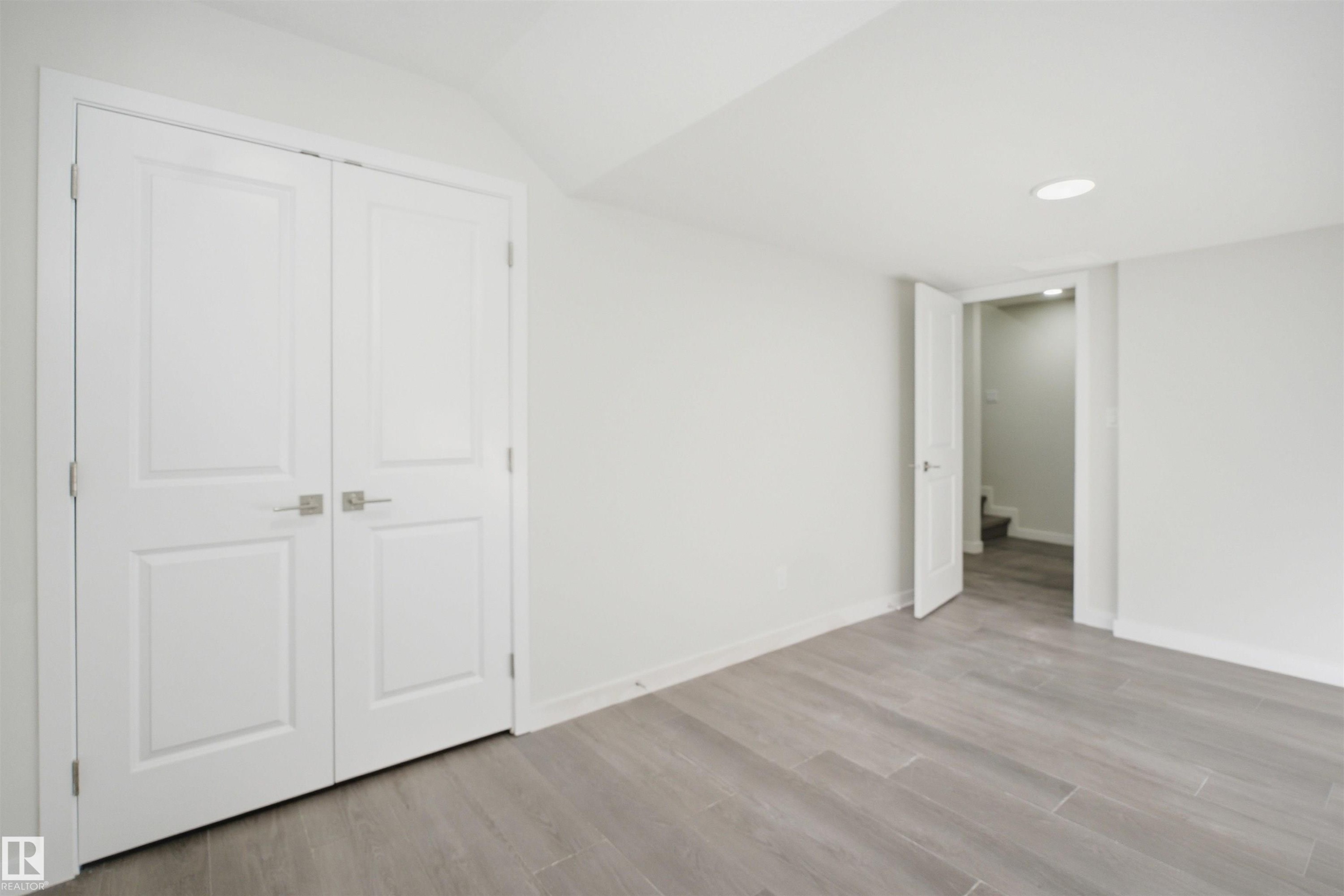 The room features light gray flooring, white walls, and bright white doors with modern square handles - 2125 Maple Road Nw, Edmonton, AB - Indoor Photo Showing Other Room