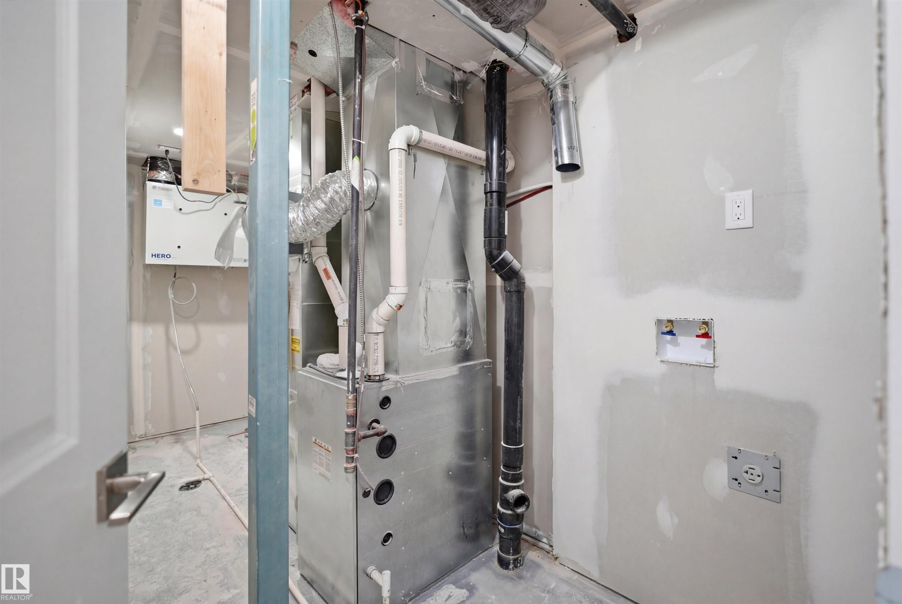 Utility area featuring a furnace, various pipes, and a white electrical outlet - 2125 Maple Road Nw, Edmonton, AB - Indoor