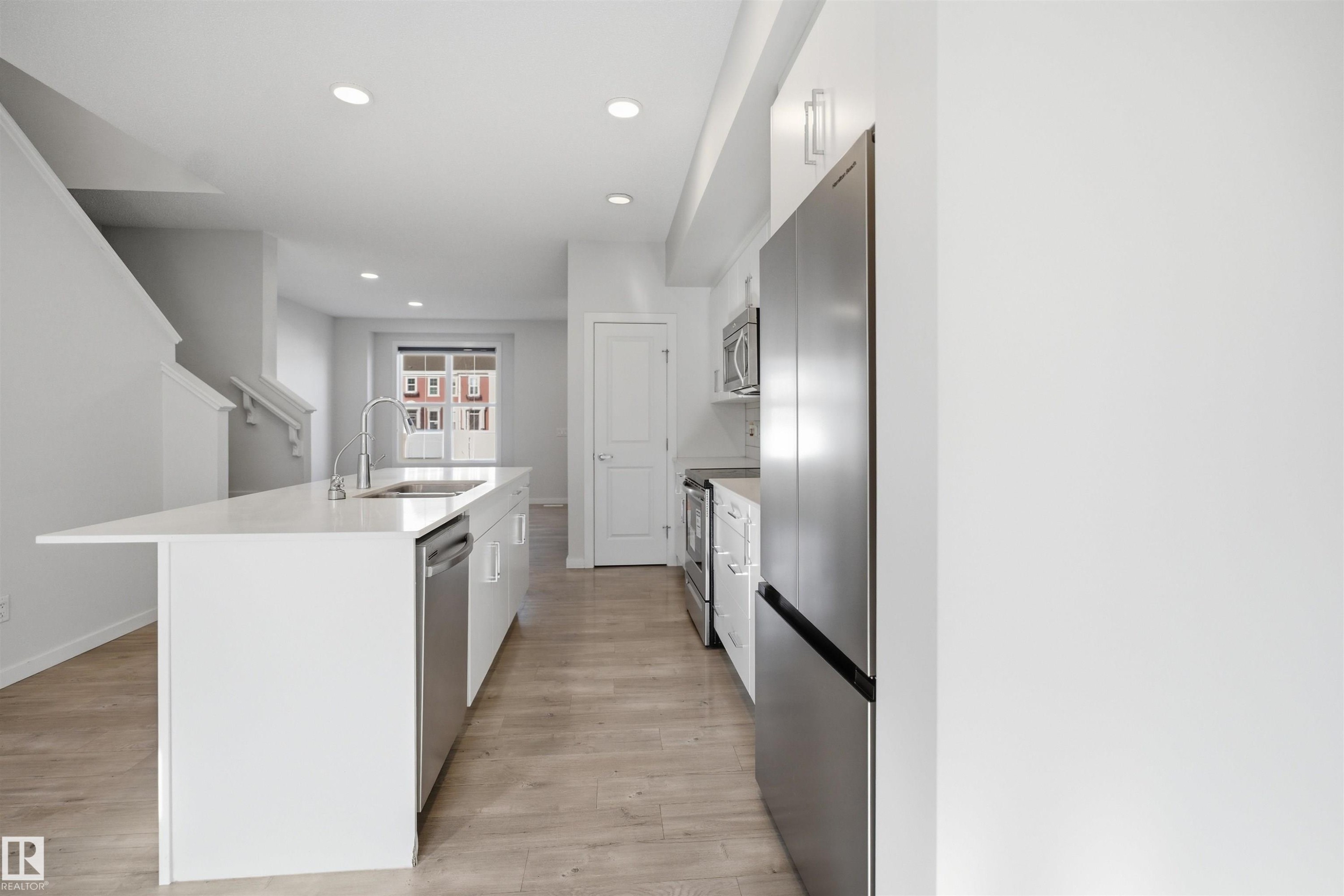 Modern kitchen featuring light wood flooring, white cabinetry, stainless steel appliances, and a central island with a sink and a dishwasher - 2125 Maple Road Nw, Edmonton, AB - Indoor Photo Showing Kitchen
