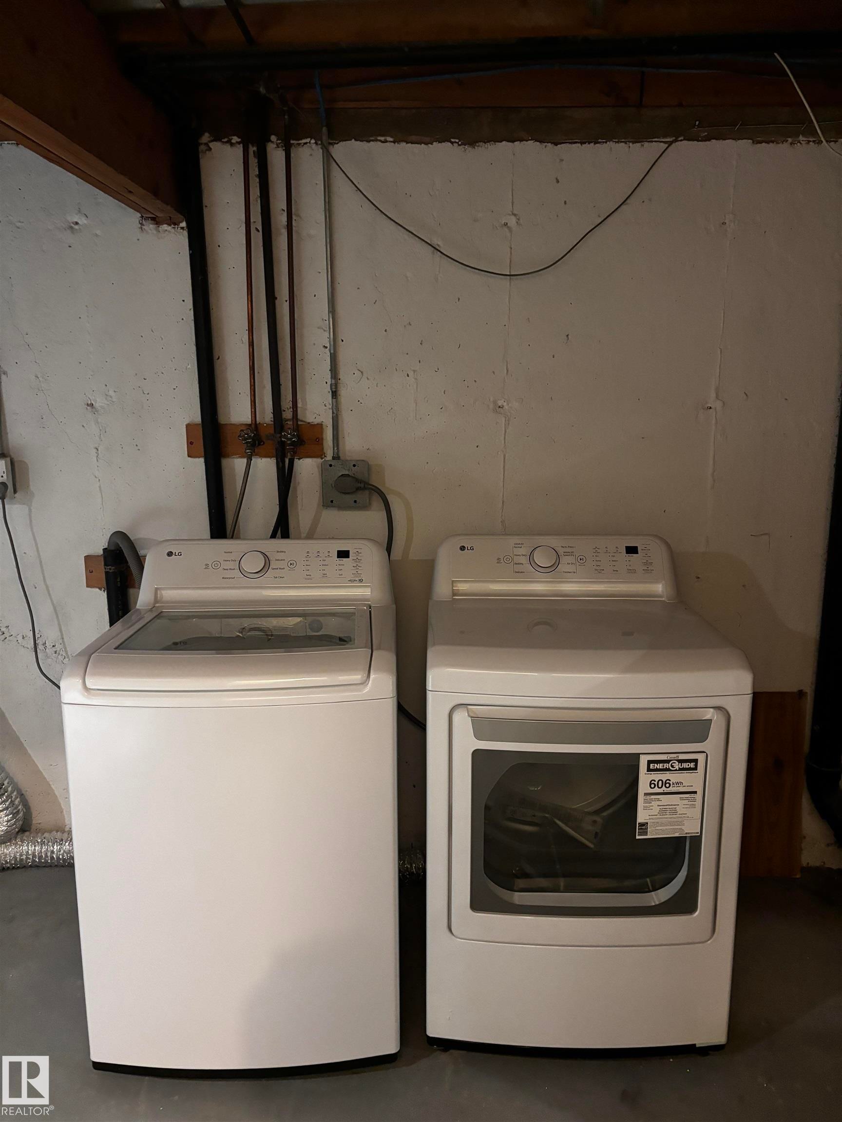 White top-load washer, white front-load dryer, concrete walls, concrete flooring, exposed overhead beams - 14075 30 Street Nw, Edmonton, AB - Indoor Photo Showing Laundry Room