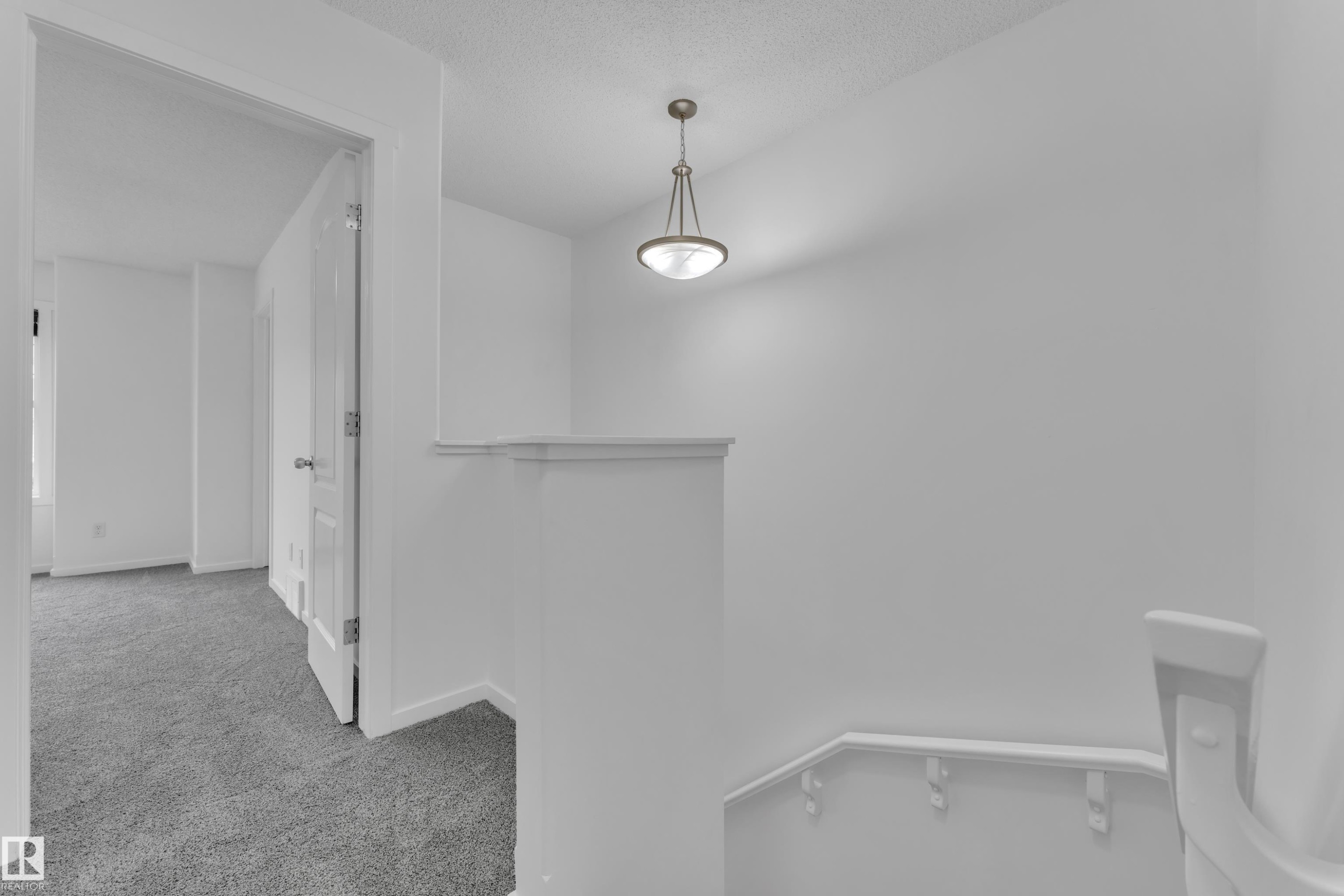 Upper-level hallway featuring a pendant light fixture, white walls, and gray carpeting - 2143 32 Street, Edmonton, AB